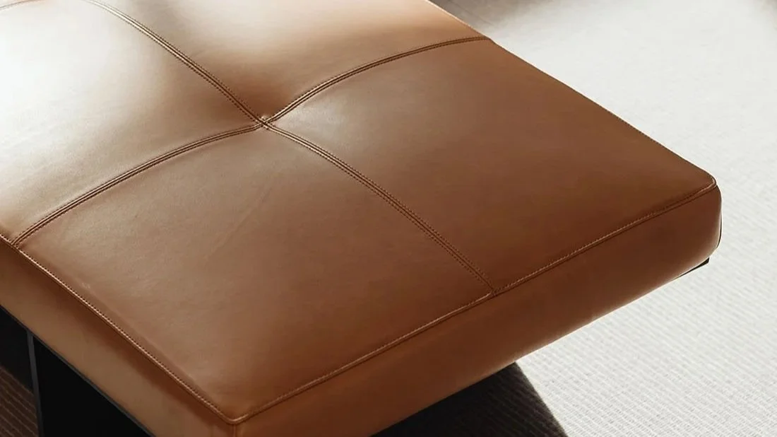 Sunlight across a brown leather bench in a warm, modern office.