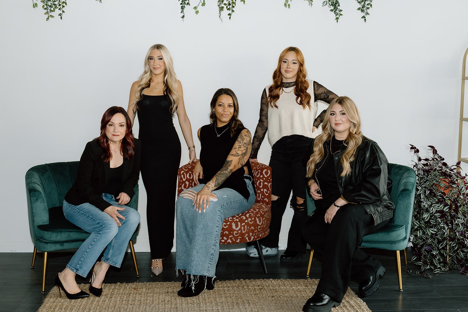 Five women sitting and standing pose and smile at the camera
