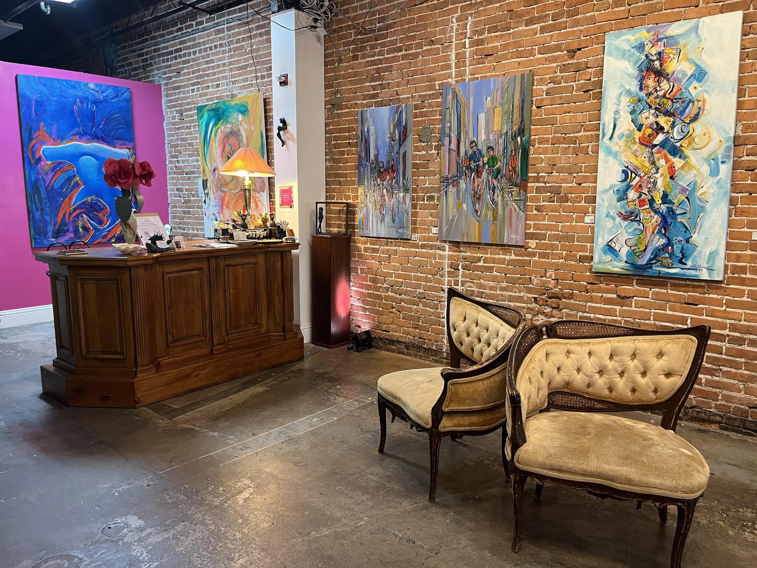 marcolinas fine arts gallery interior with two chairs, reception desk, and five abstract paintings on the wall.