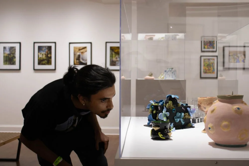 Gallery visitor peers at art through display case.