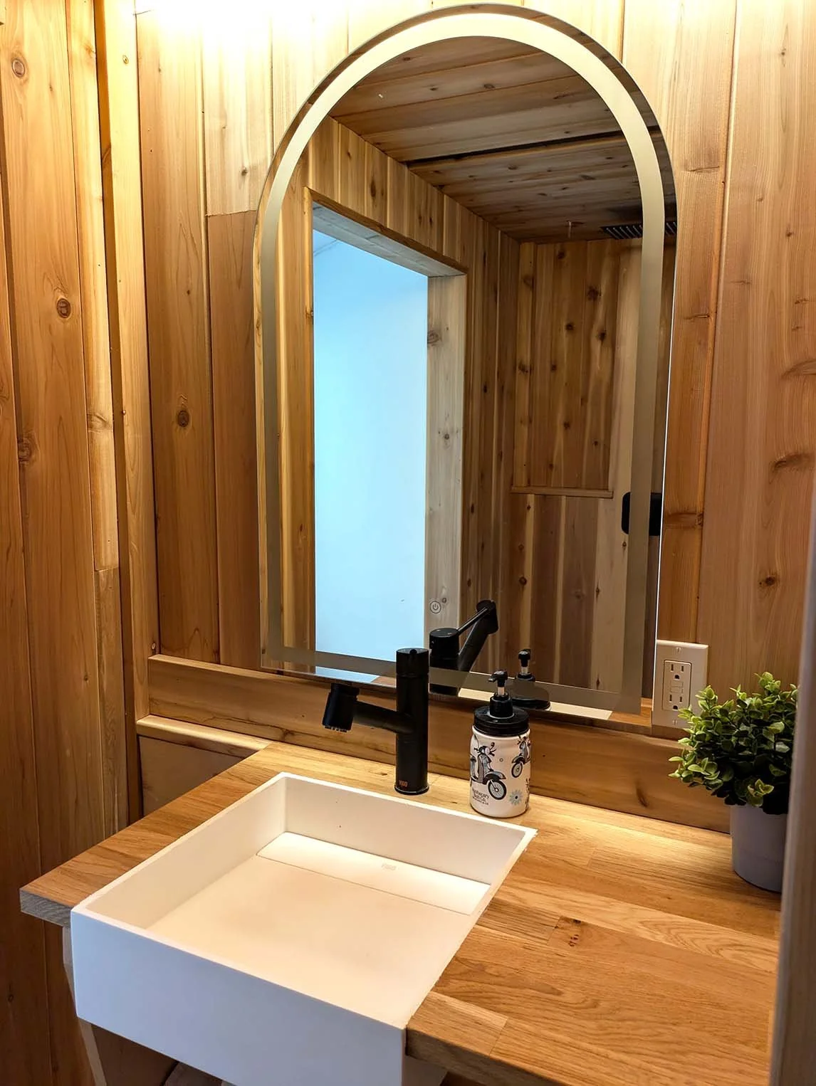 Bathroom vanity inside the HONE Showcase build by MonX Design, full cedar bathroom, white sink, round mirror