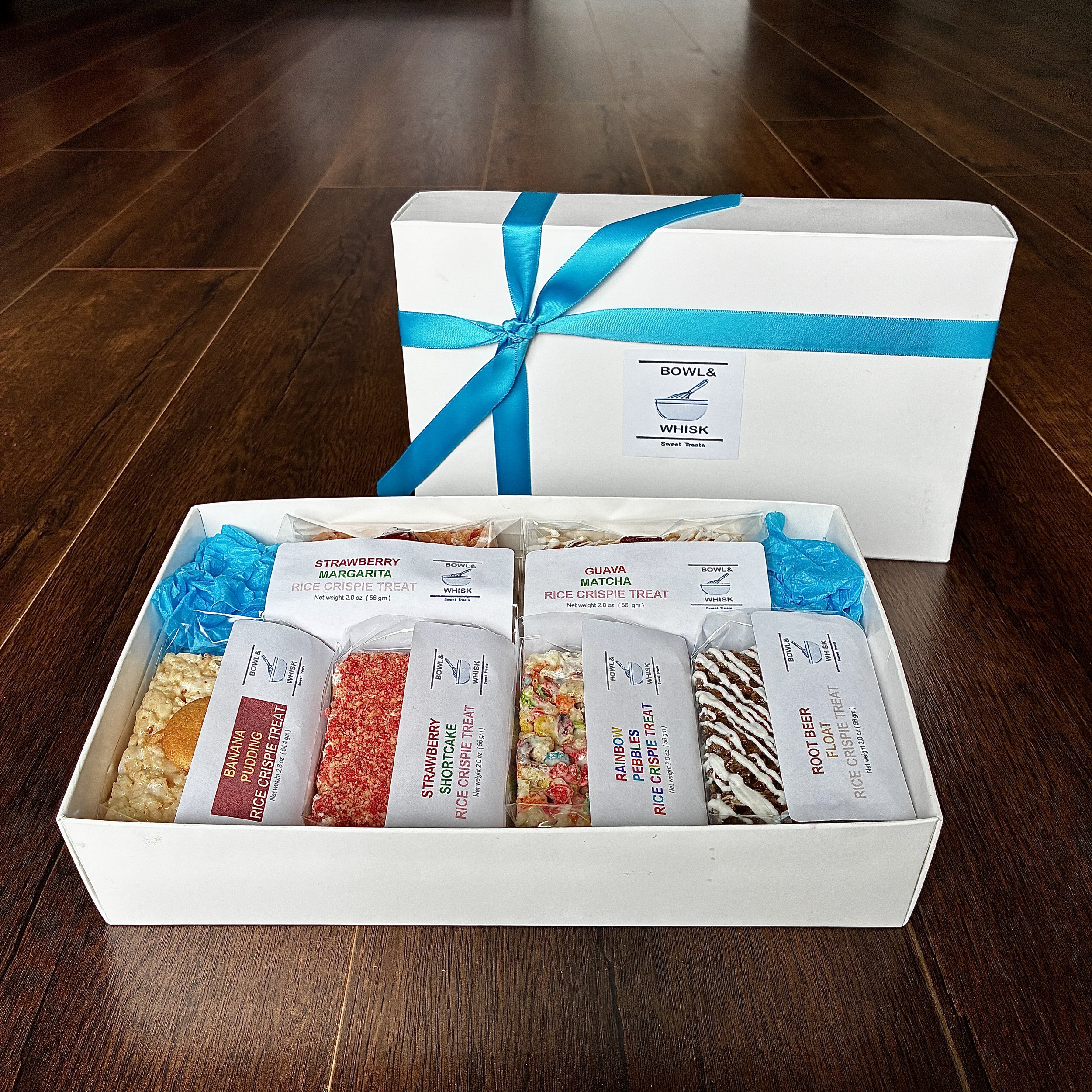 Our August 2026 Gift Box of Individually Wrapped Rice Crispie Treats, containing 1 piece each of banana pudding, guava matcha, rainbow pebbles, root beer float, strawberry margarita and strawberry shortcake flavors.