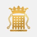 A golden trophy with a crown on top, featuring chain handles on each side and a checkered base.