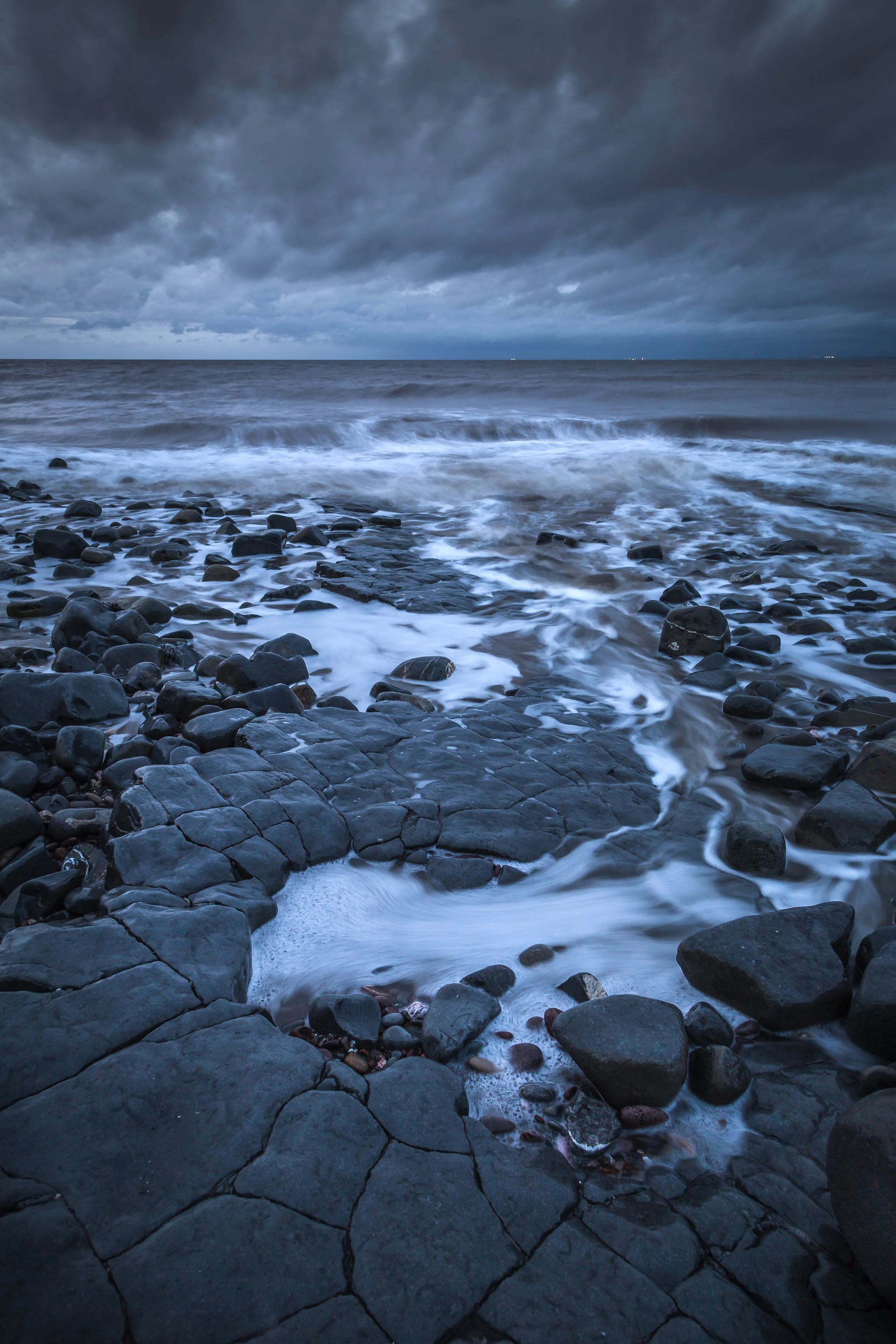 Rocky beach with waves under a cloudy sky