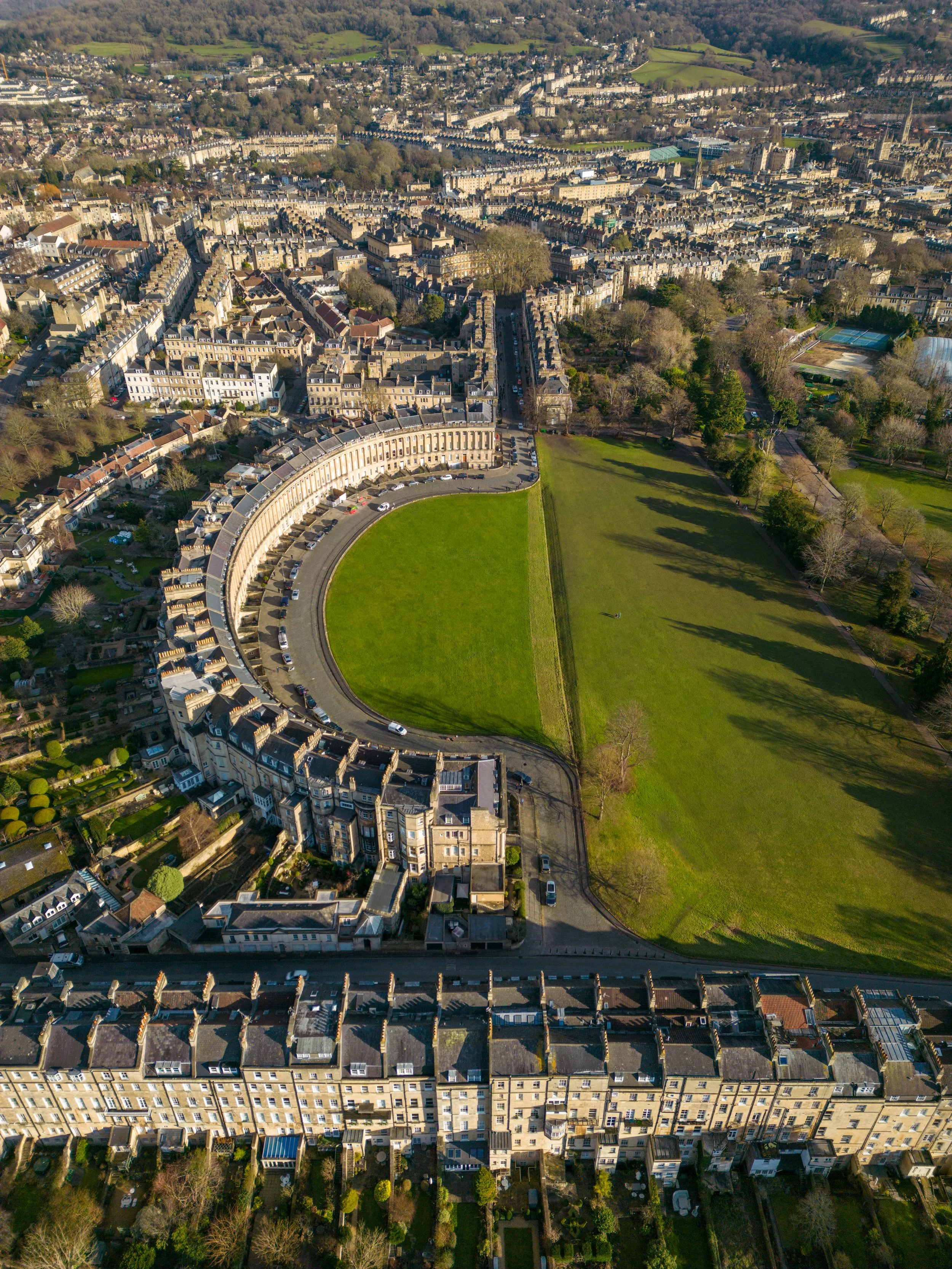 Aerial view of a city neighborhood with a crescent-shaped row of houses surrounding a green park.