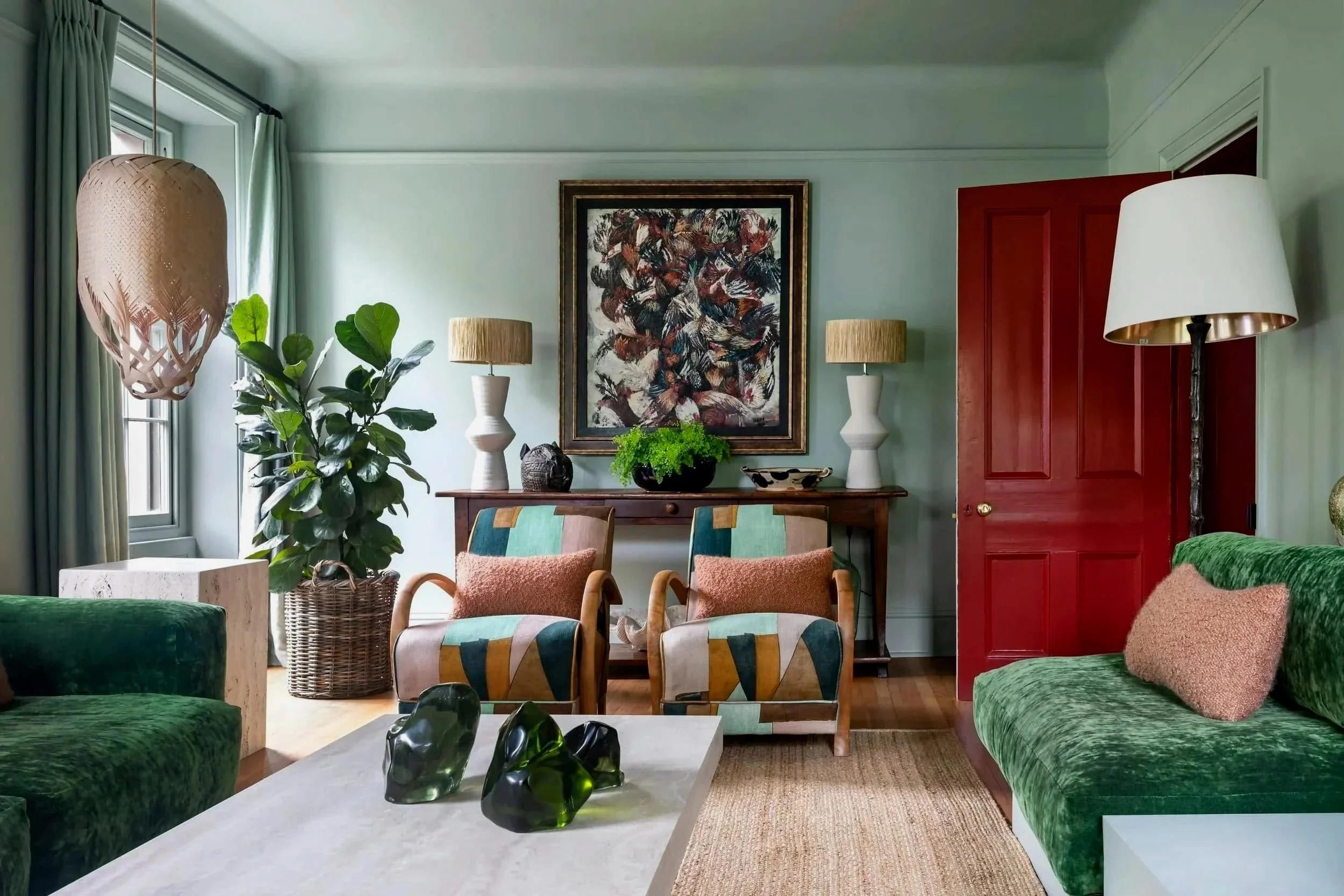 "Sitting room with green velvet sofas, patterned armchairs and a red door in a Jersey granite farmhouse, designed by Bryony Richardson"