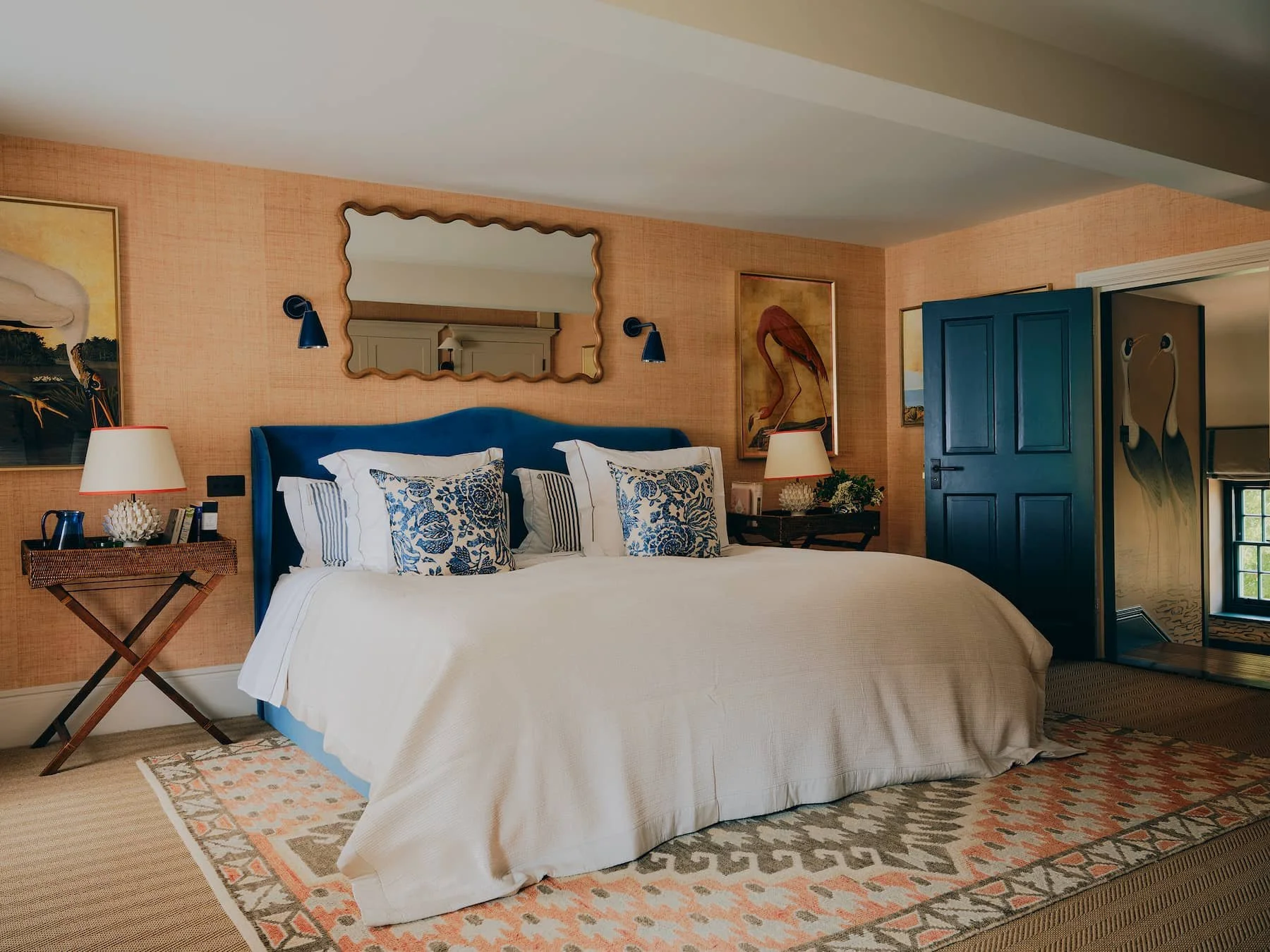 Cosy Master Bedroom with coral woven wallpaper, velvet headrest and sisal carpet in rural rectory in Jersey