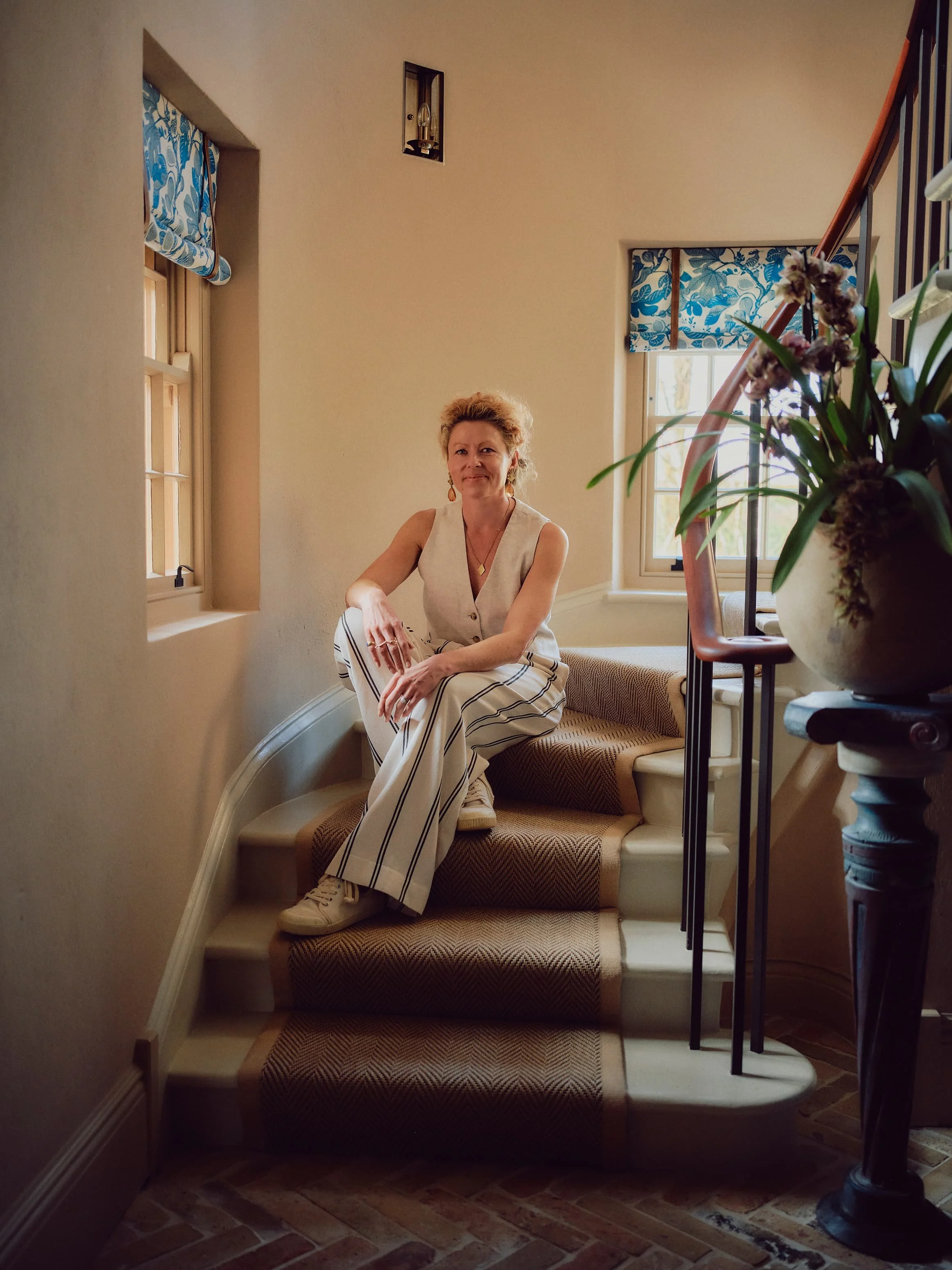 "Bryony Richardson, interior designer based in Jersey, sitting on a staircase in a Jersey period property"