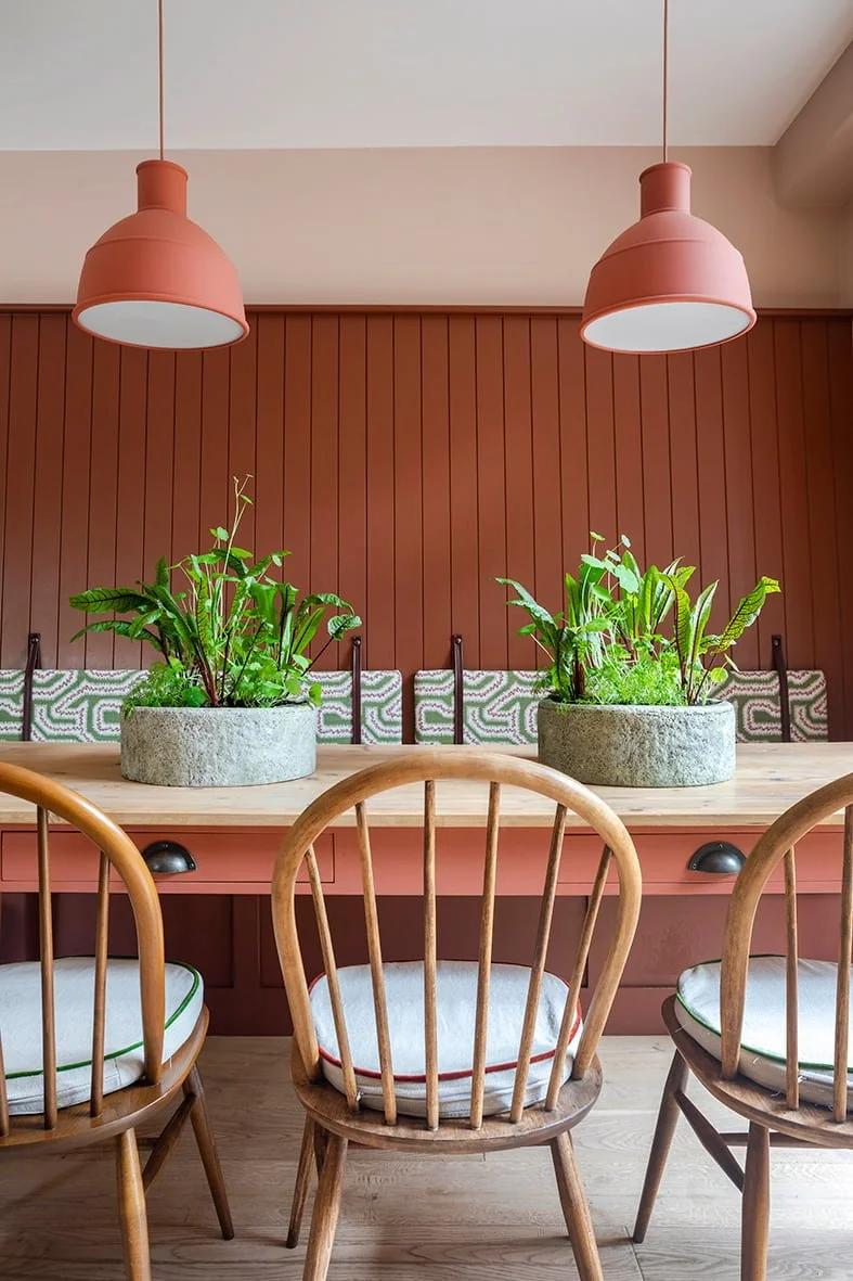 Dining table with terracotta pendant lights, backrest seating and vintage chairs in a Georgian Villa in Jersey