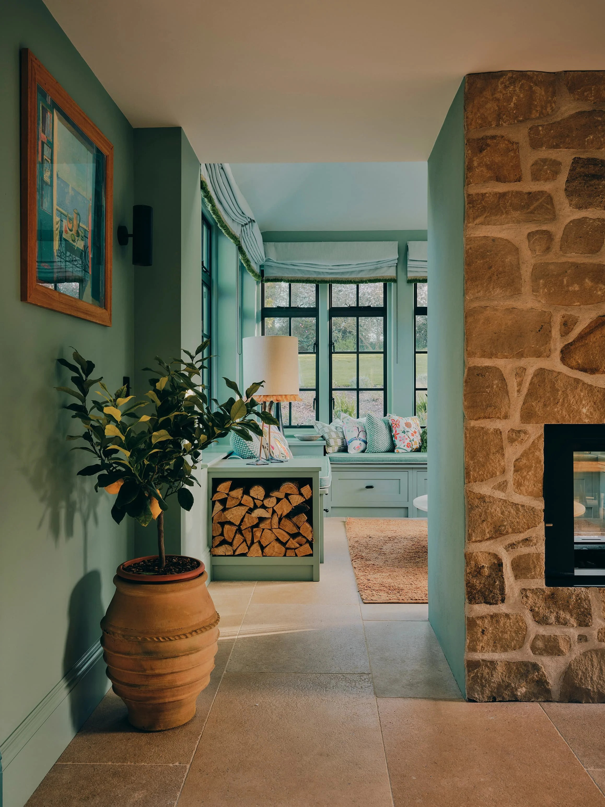 "Garden room with stone fireplace and potted lemon tree in a Jersey rural rectory by Bryony Richardson"