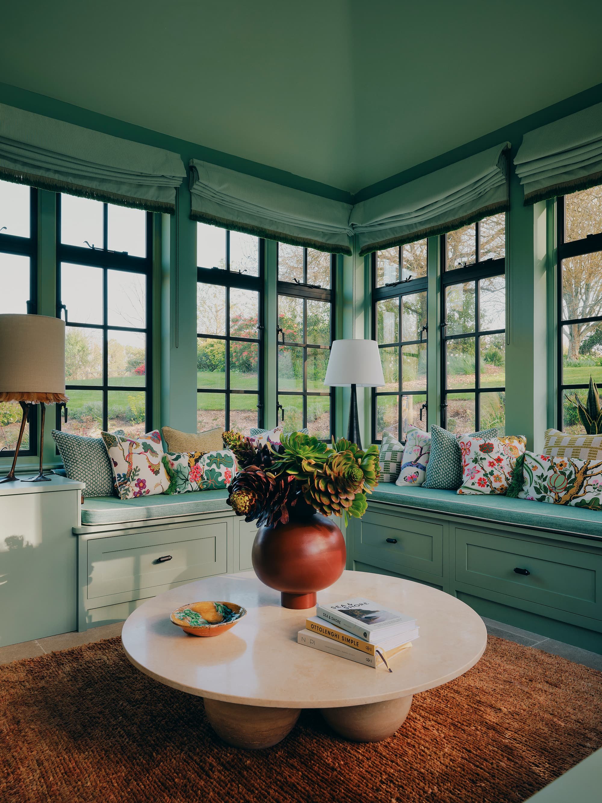 Turquoise Orangery with floral-themed cushions and marble table with views to Rural Rectory garden in Jersey