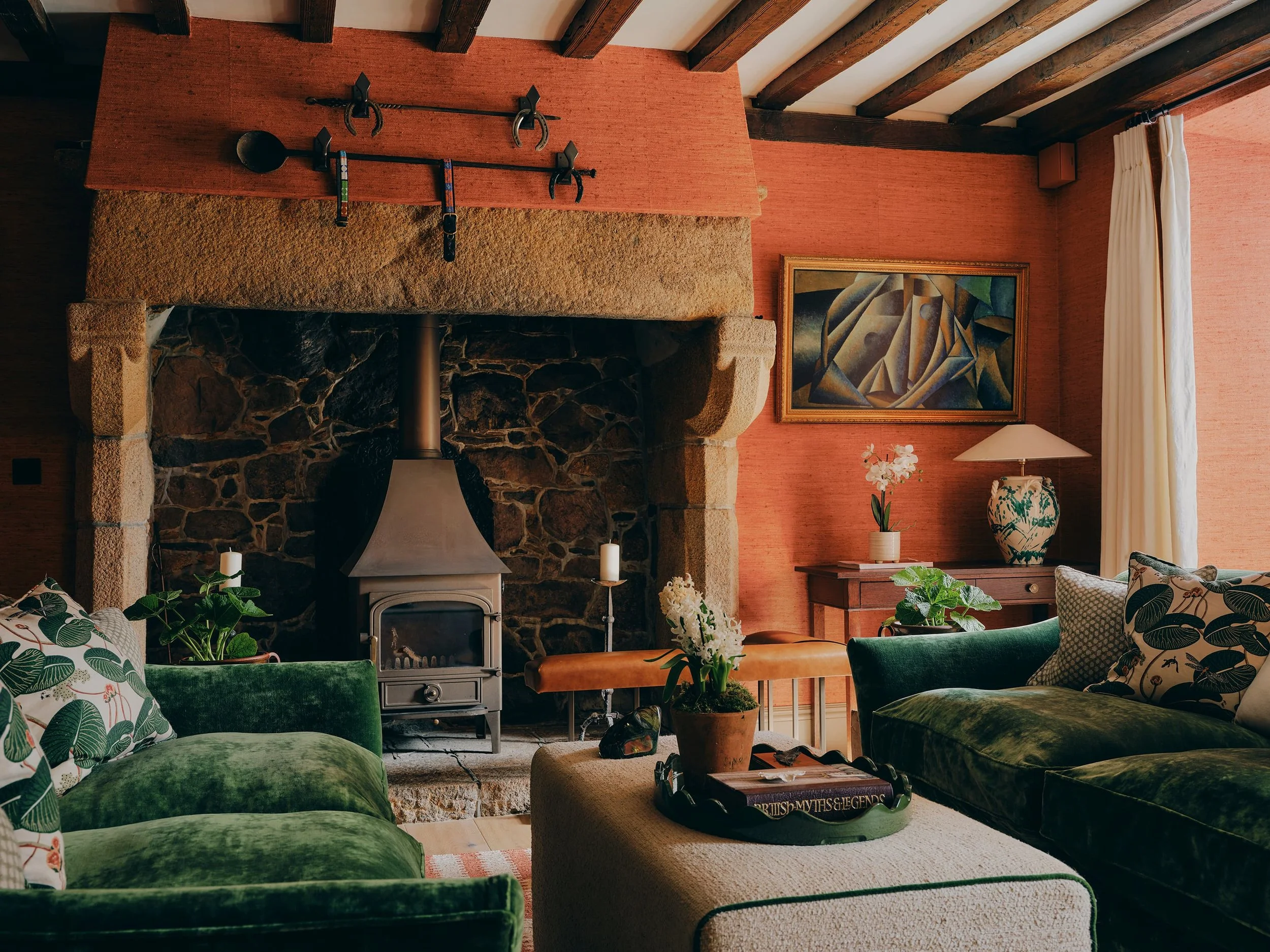 Living room with inglenook fireplace and green velvet sofas in a Jersey rural rectory by Bryony Richardson