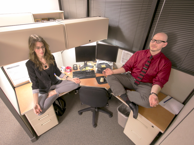 Ann Swanson and a man meditating on top of an office desk