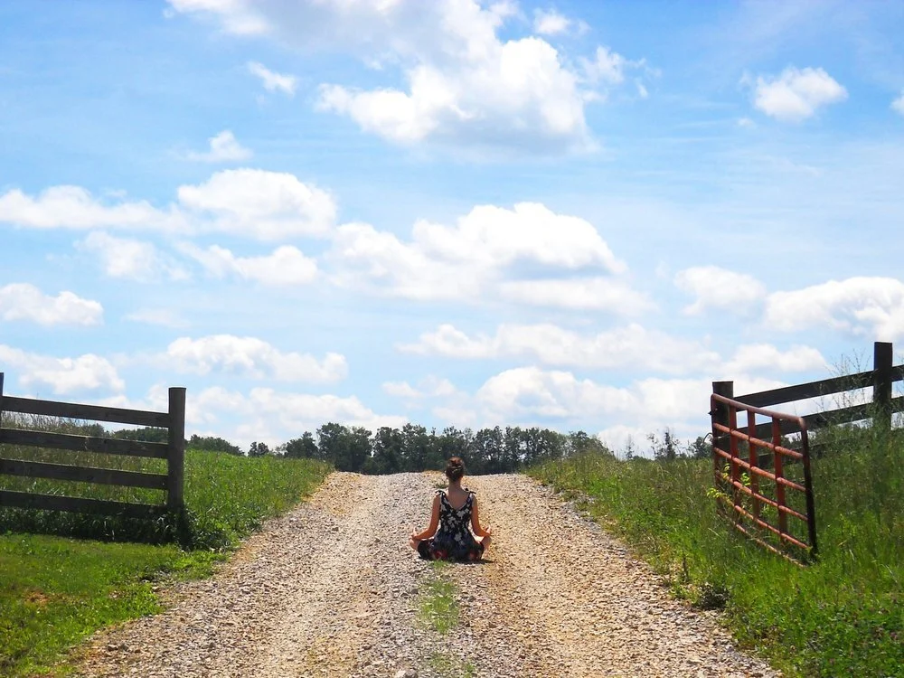 Ann Swanson meditating in nature and a bright blue sky