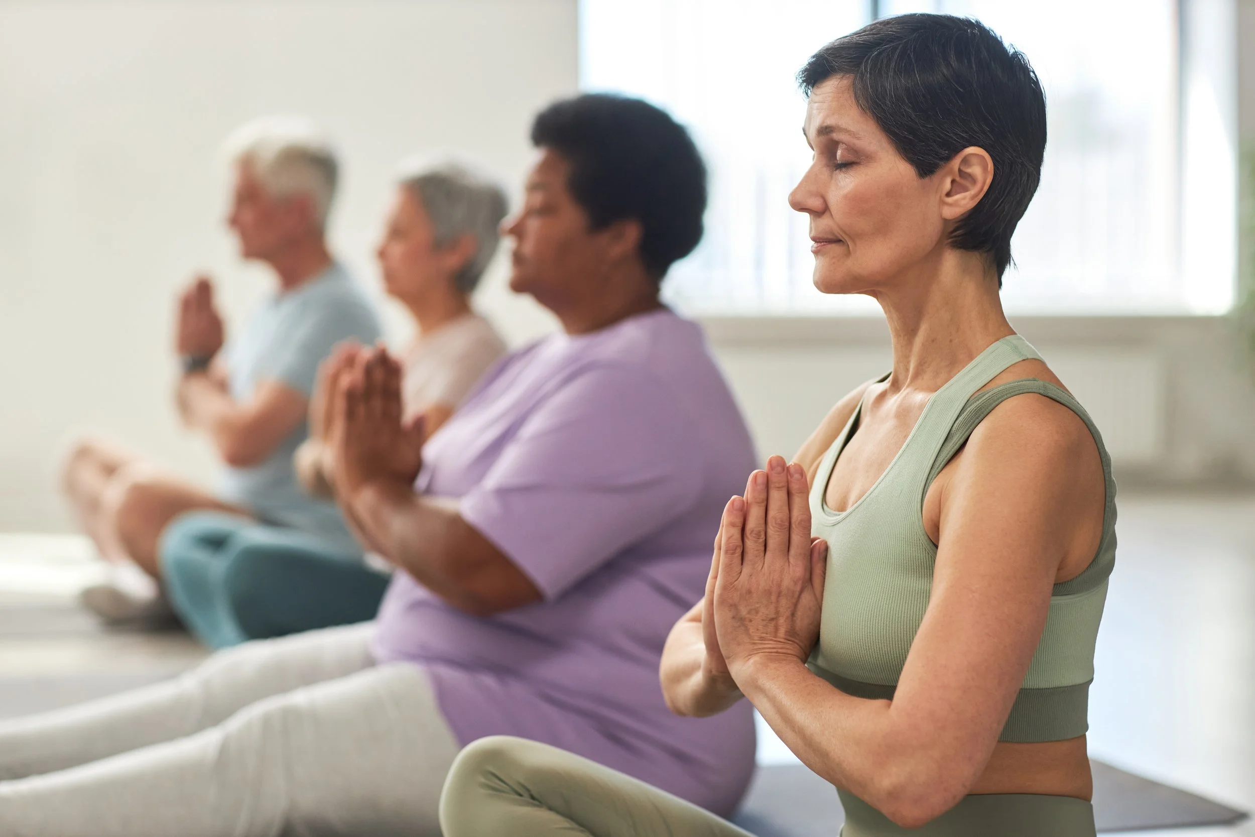 4 people meditating in yoga class.