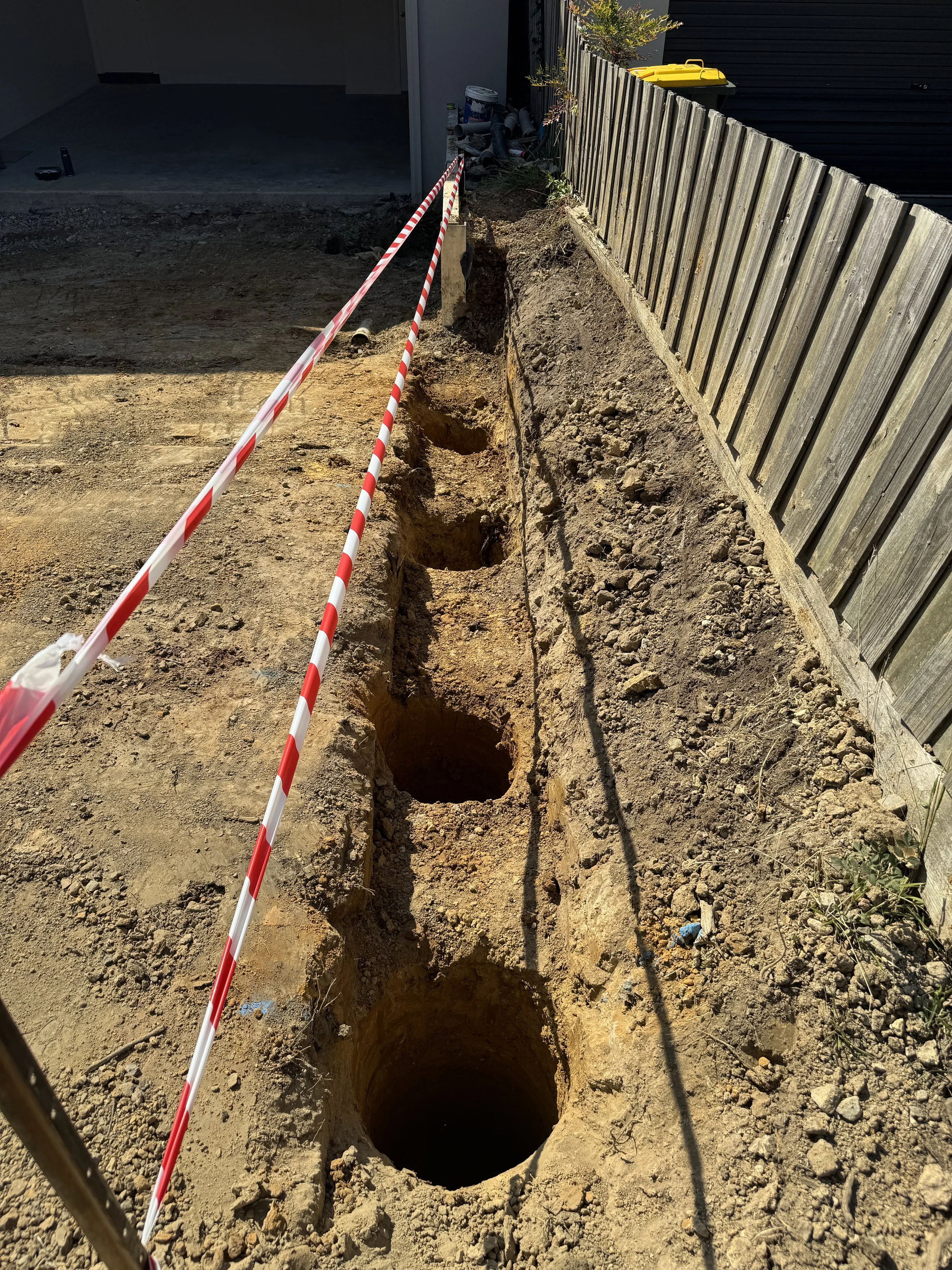 Auger post holes for a retaining wall