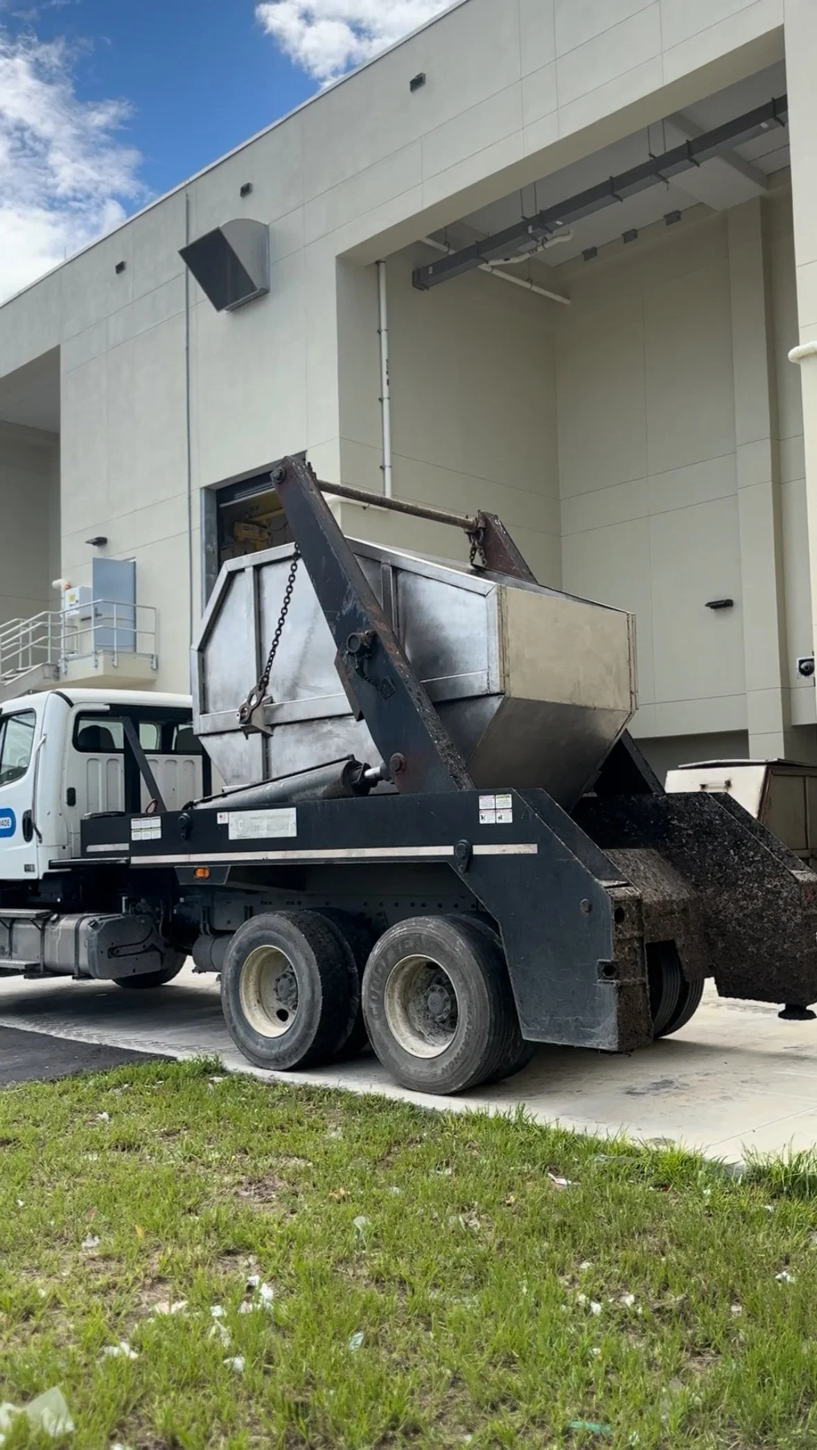 A dump truck parked outside a modern building with a large loading dock area.