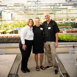 Two women and man smiling in greenhouse