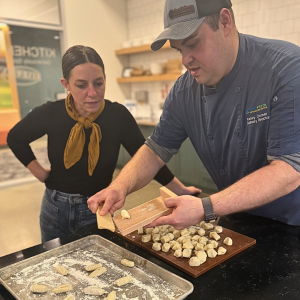 Man showing woman how to roll gnocchi