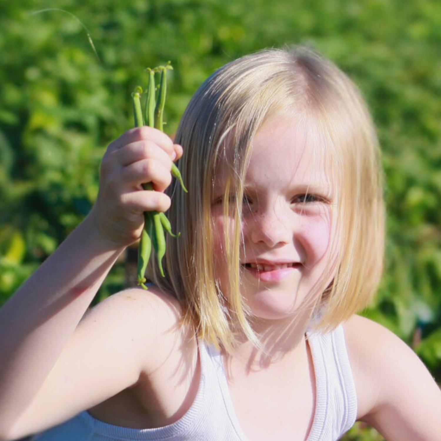 Girl with handful of green beans in field