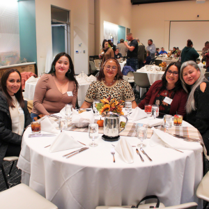 Women smiling for photo around table during an evening celebration