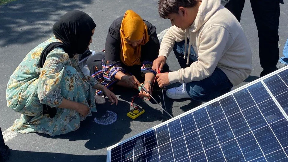 Teens working on a solar panel outside
