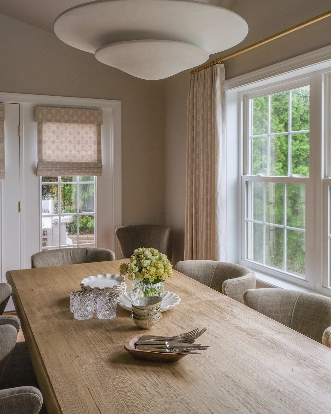 Soft neutrals and layers of texture make this Gulph Mills dining room feel instantly inviting. The mix of warm wood tones, patterned shades, and fresh florals adds just enough personality while keeping everything calm and cohesive. We take the time t