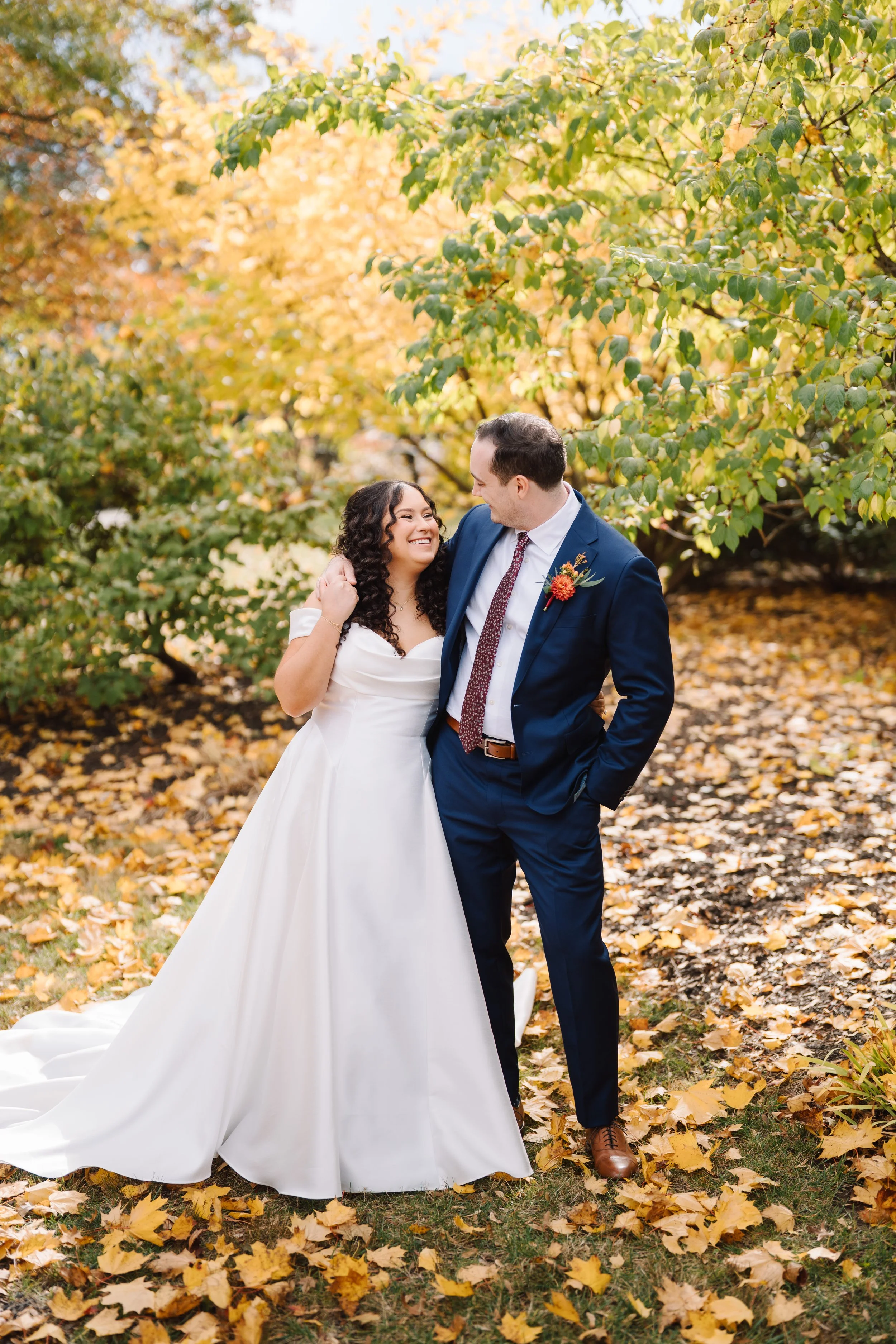 Bride and groom posing in leafs at Aldie Mansion