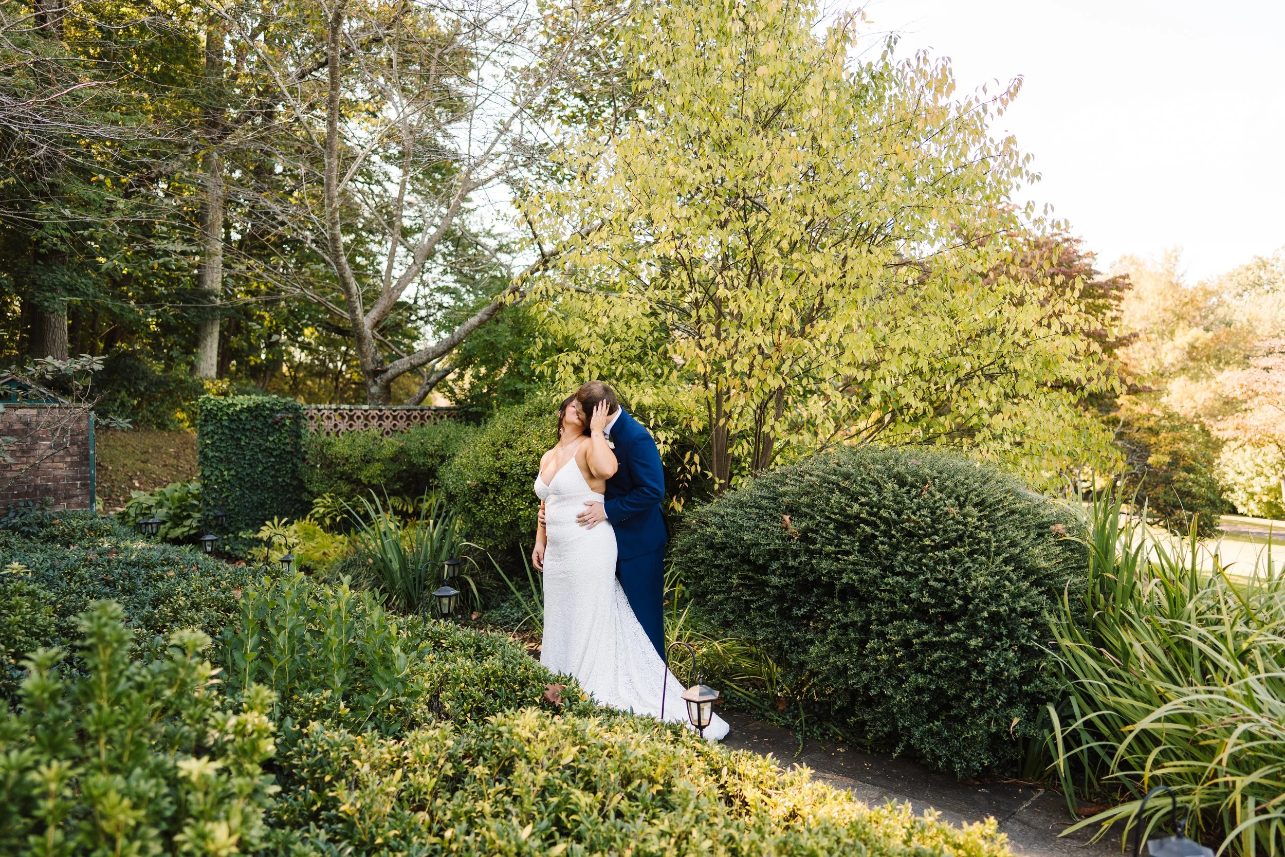 Bride and Groom kissing on a path.