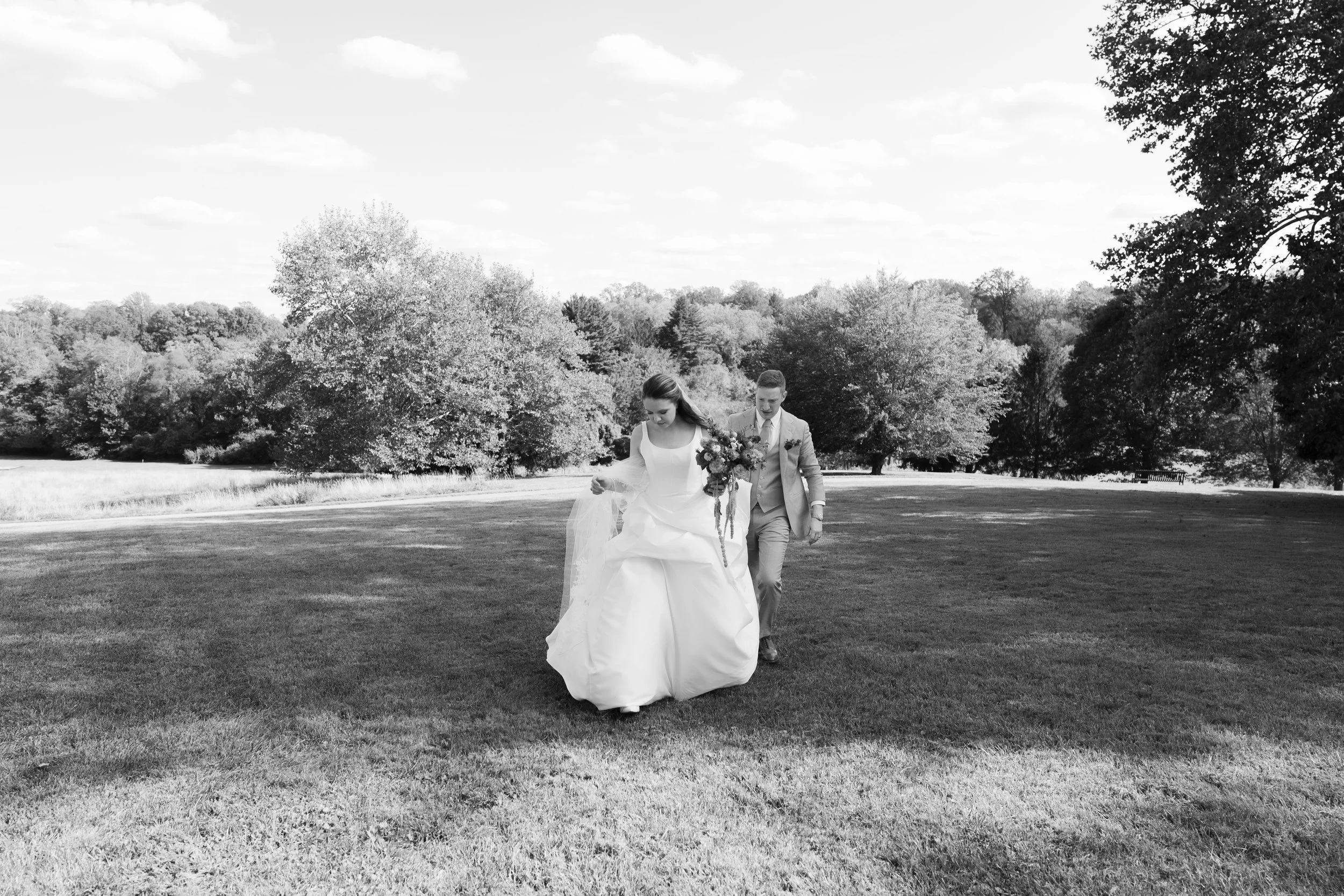 Bride and groom walking up a hill together at Hilltop House.