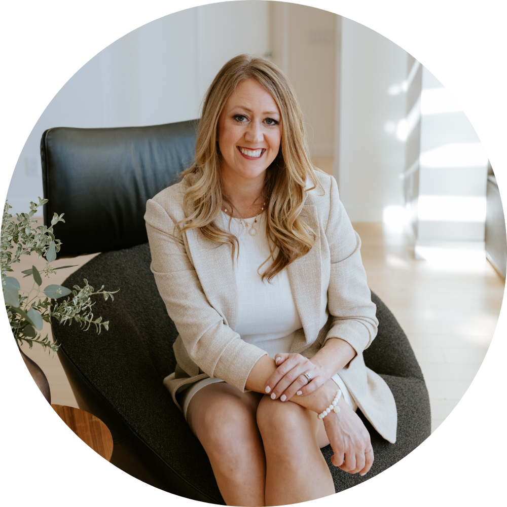 Best Financial Planner Winnipeg Candace Landry sitting casually smiling on a leather chair, wearing a tan suit jacket and skirt.