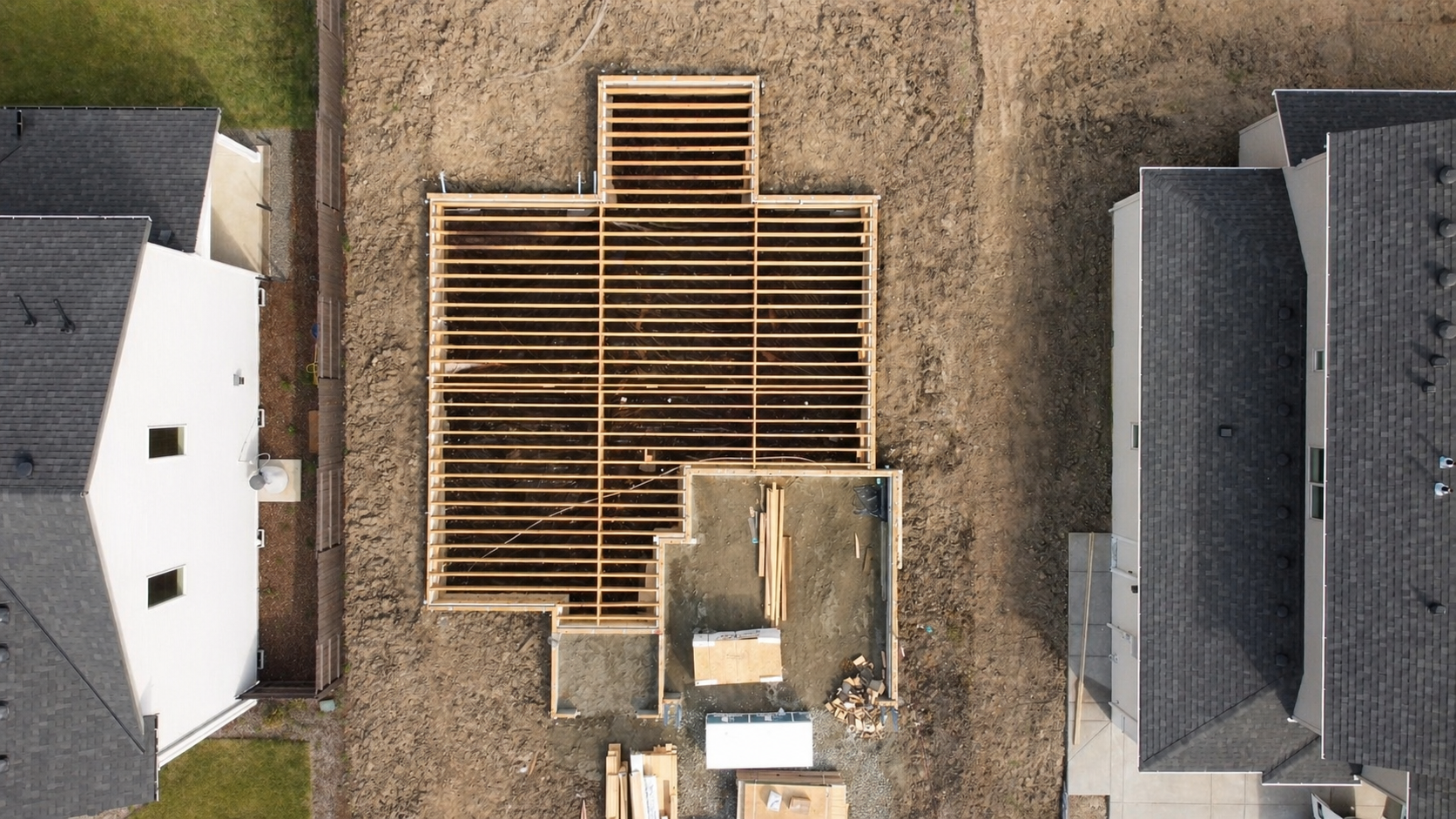 Aerial view of custom home floor framing under construction, showing the wood joist layout and early structural work by Anthropos Design.