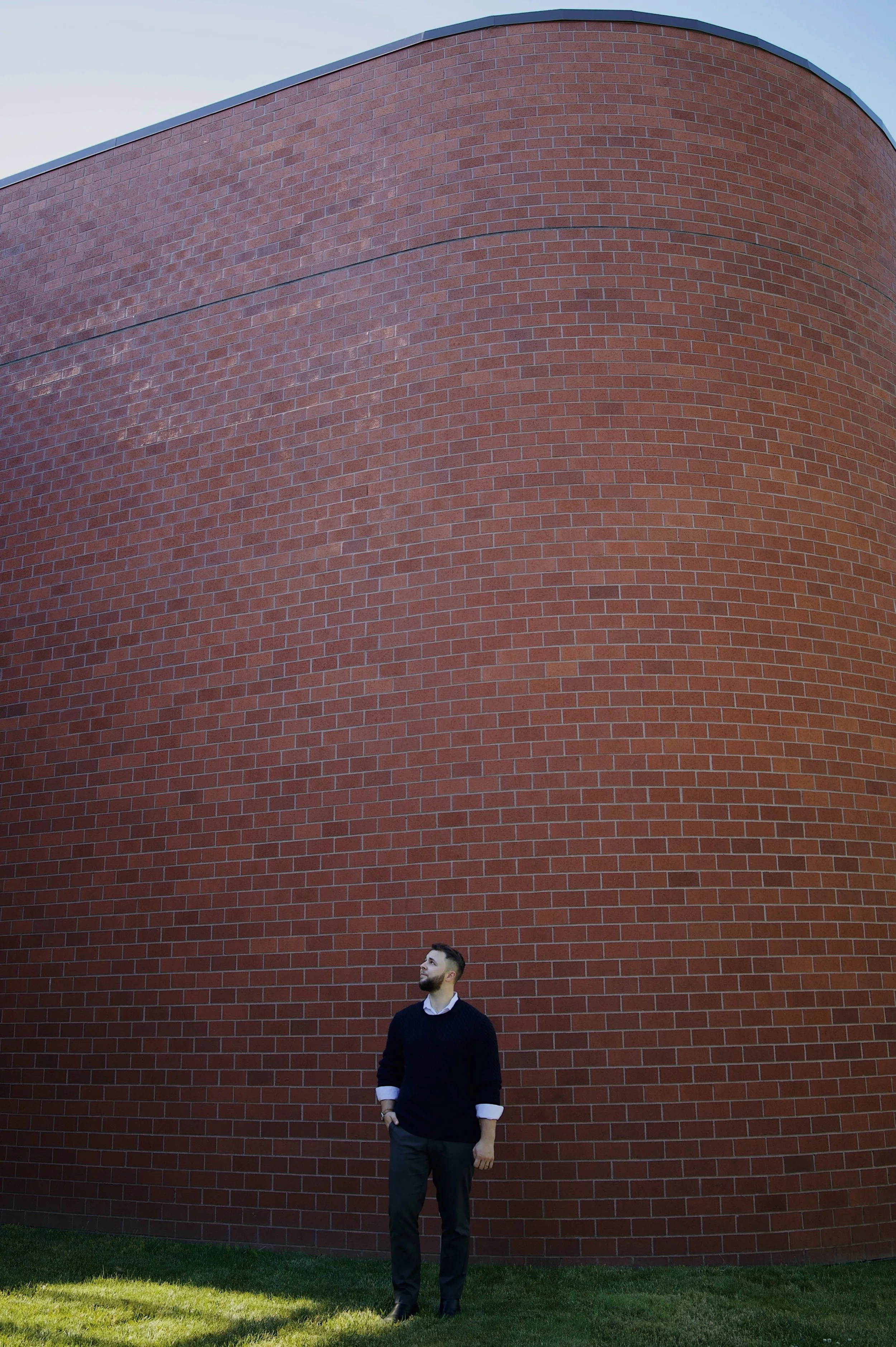 Anthropos Design Studio founder standing beside a curved brick wall in Portland, Oregon.