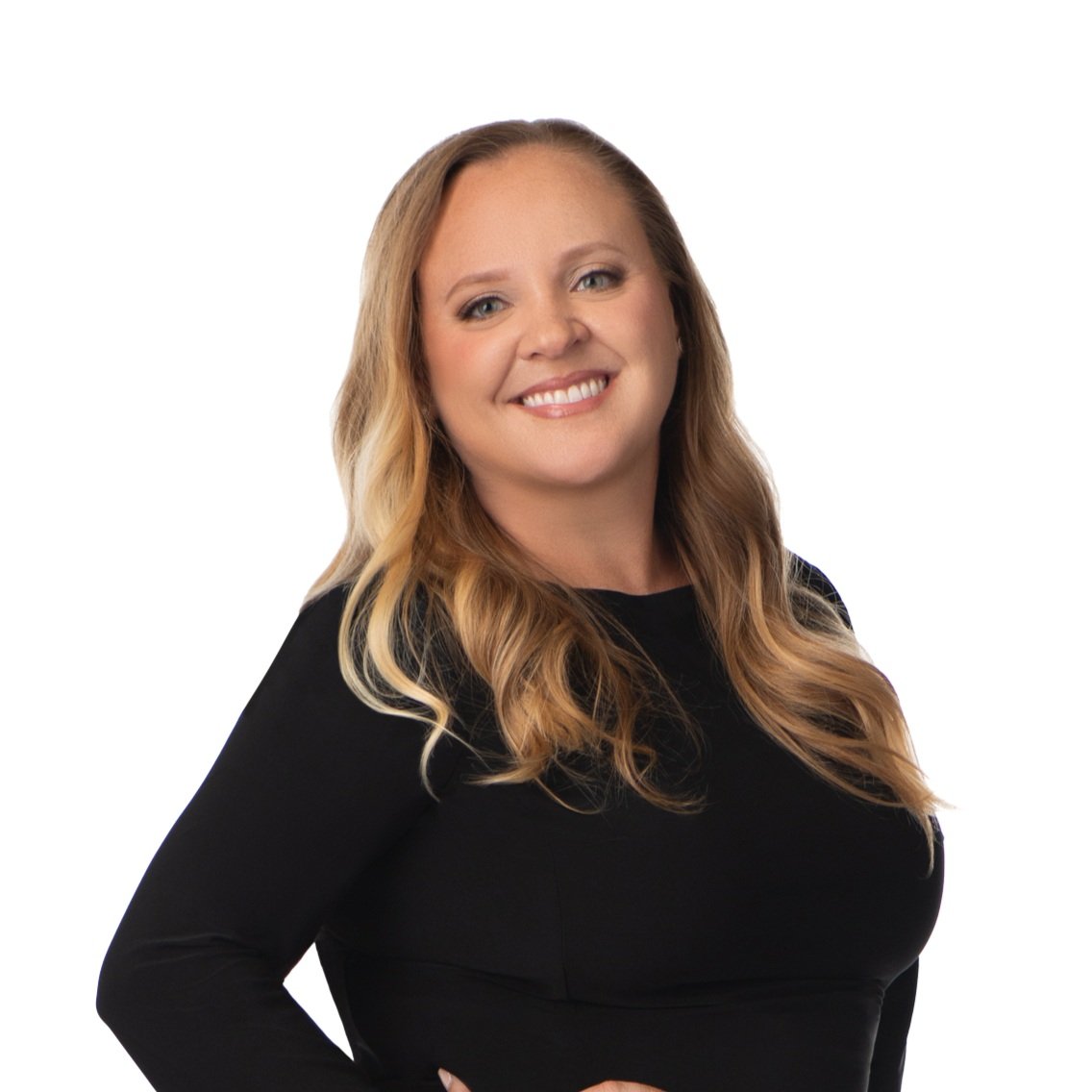 Smiling woman with long blonde hair wearing a black dress, standing against a white background.