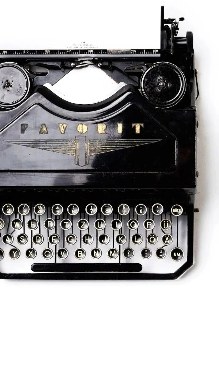A vintage black typewriter with round keys spelling out the word "FAVORIT" and the German alphabet, featuring special characters such as umlauts.