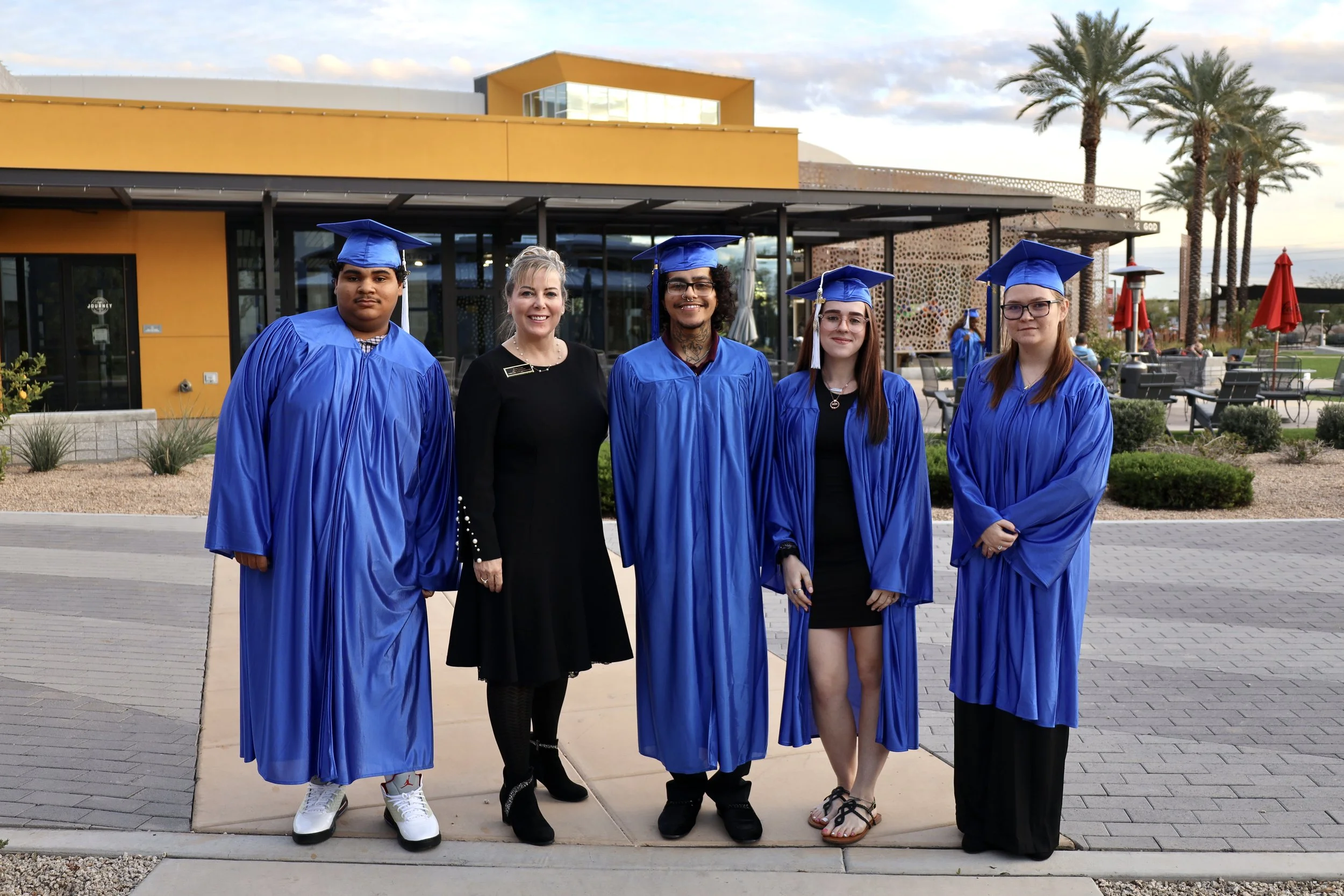 A group of graduates standing with their mentor at their graduation ceremony