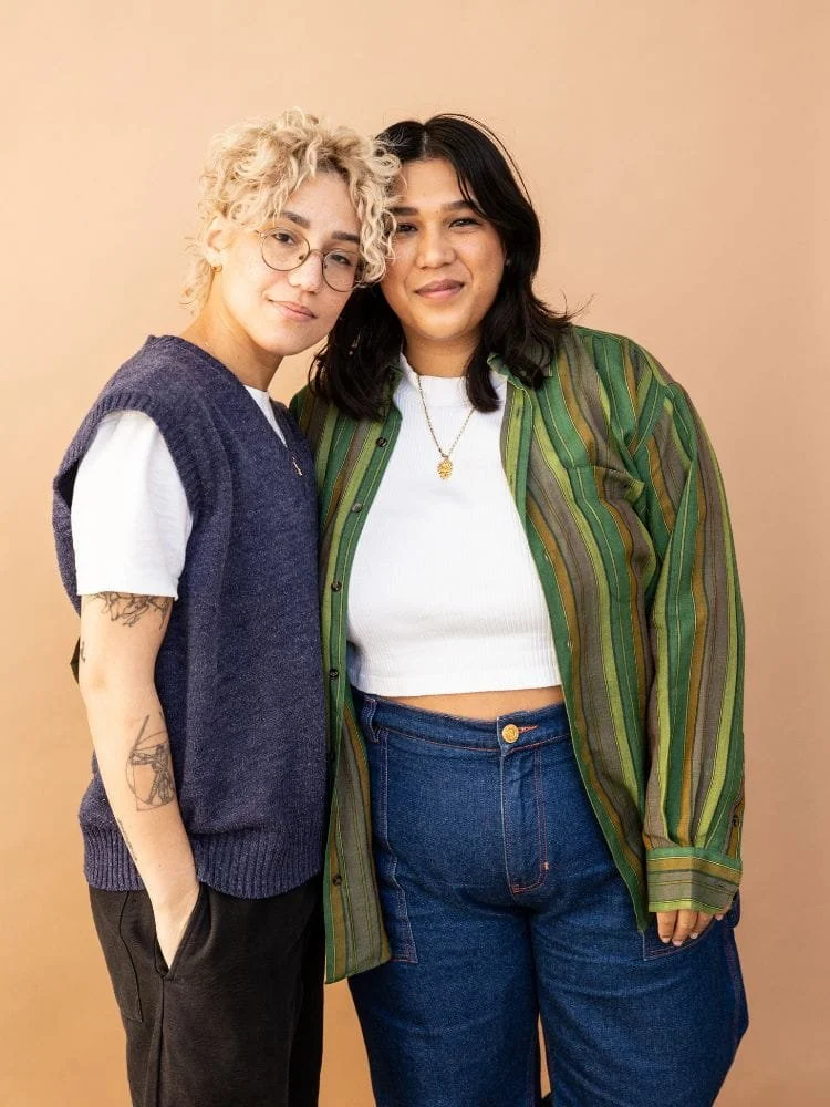 Queer couple standing next to each other and smiling into the camera