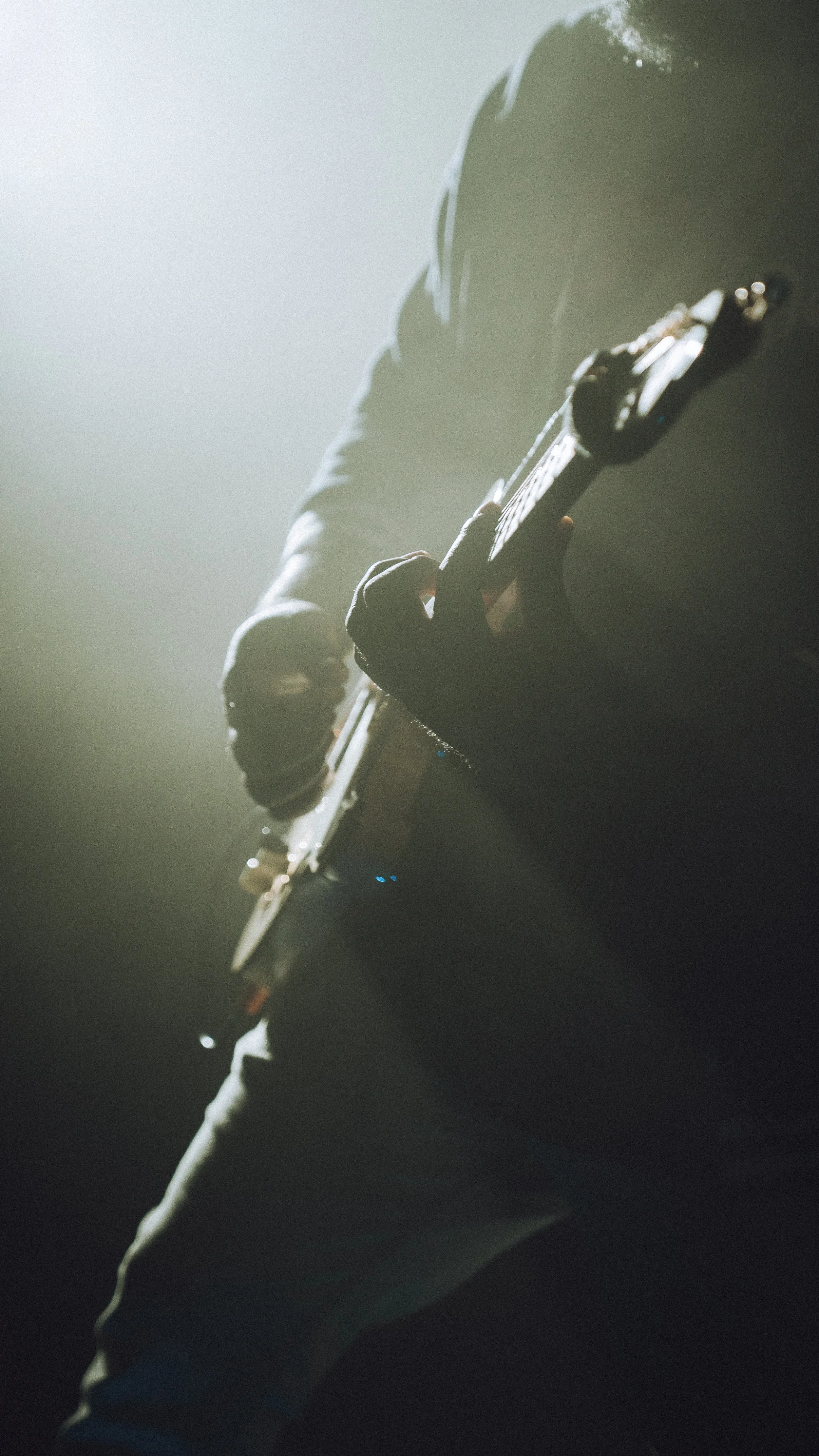 Person playing an electric guitar in a dimly lit environment.