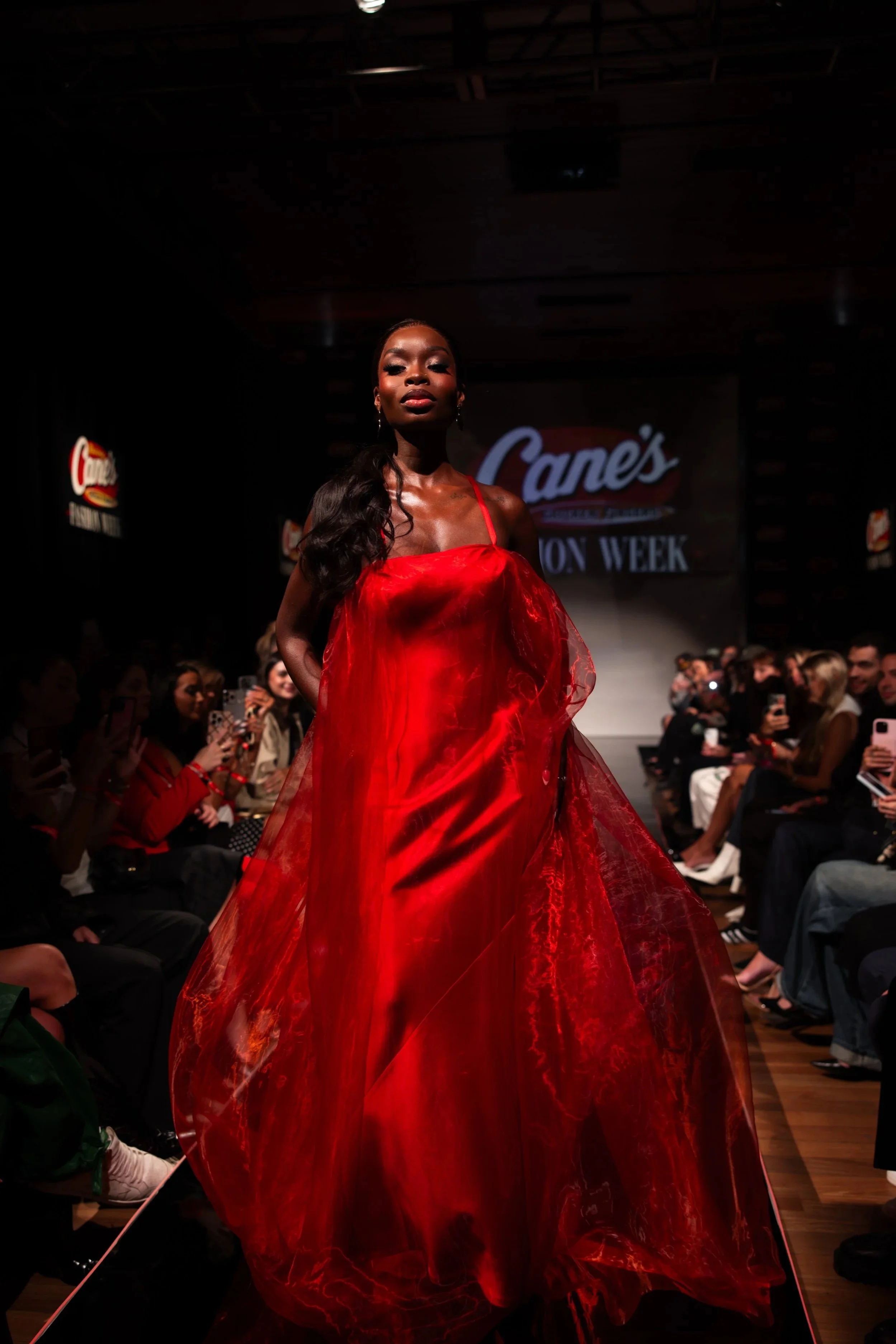 Model in a red gown on the Raising Cane’s Fashion Week runway