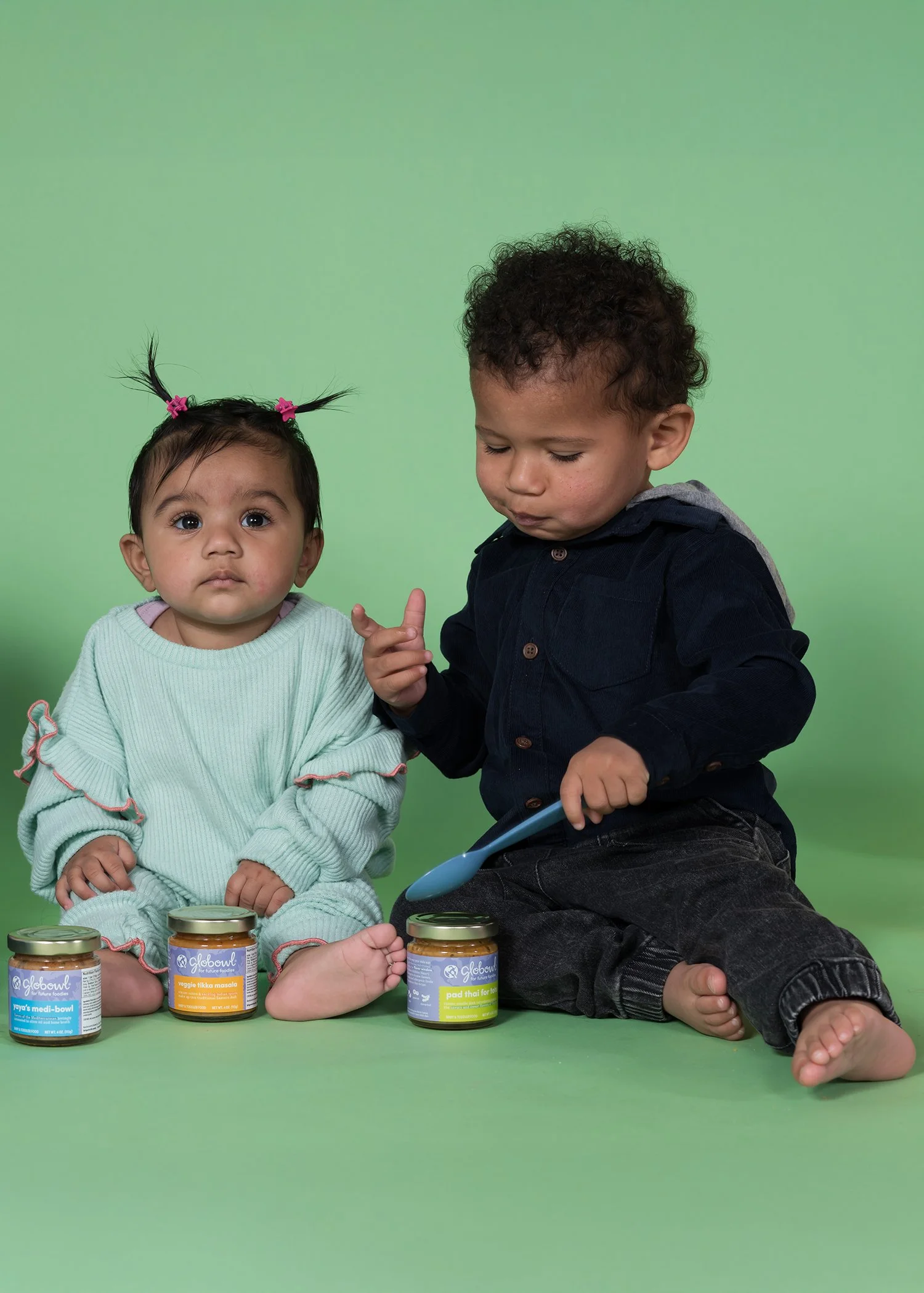 2 toddlers eating baby food on green background studio photography.JPG