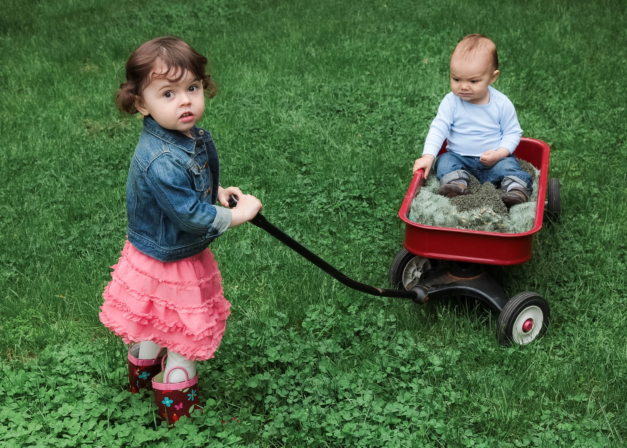 lifestyle portrait of toddler girl bulling baby boy in red wagon.JPG