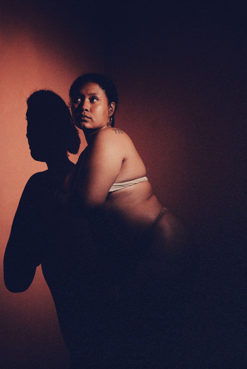 Unmasked
 (30x40in):

Light and shadow dance on her skin. Each curve and crease is a testament to presence. She does not shrink. Instead, she expands herself, letting darkness hold her without consuming her. This is reclamation of body, of gaze, of s