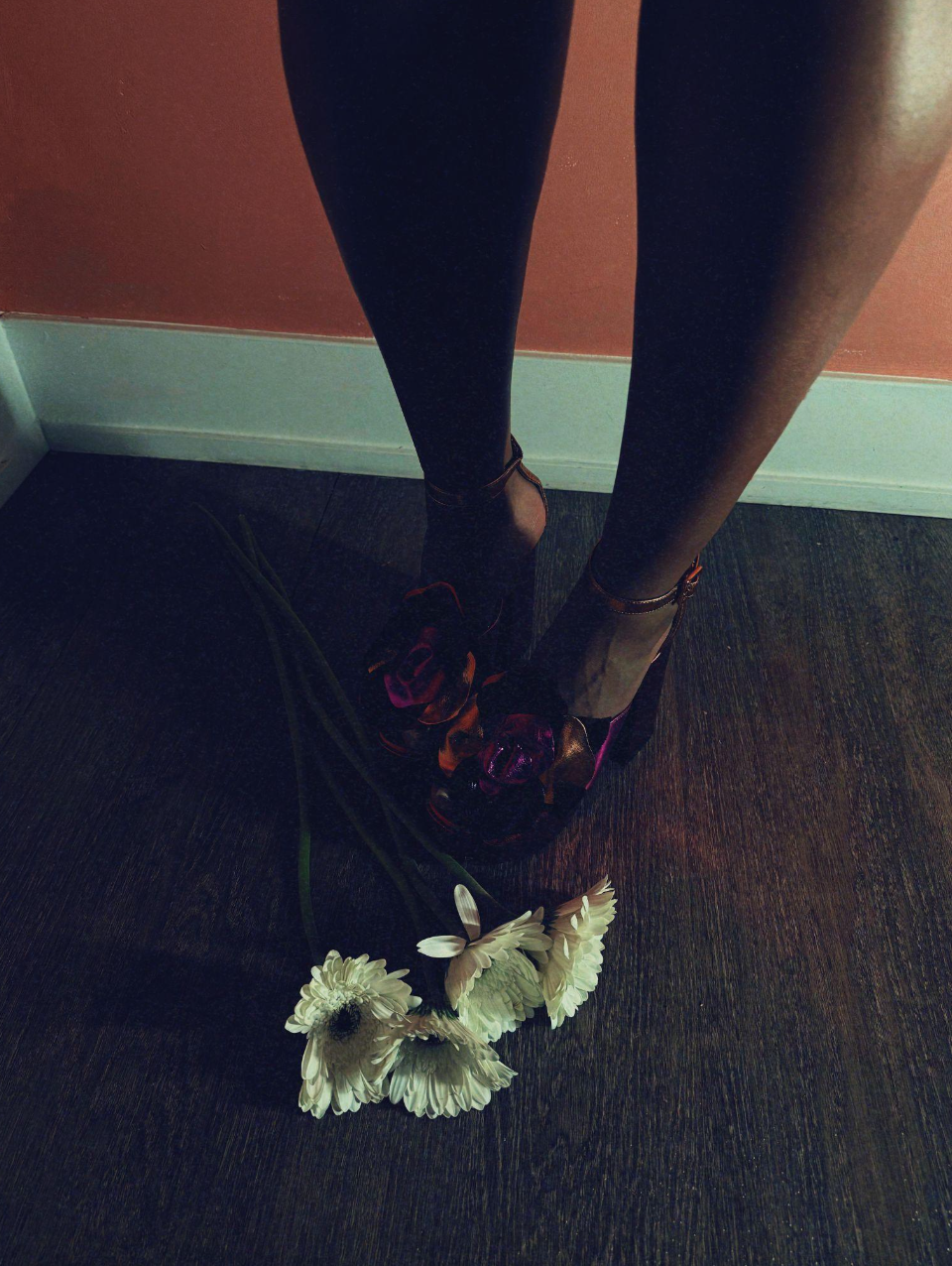 Aftermath
(30x40in):

In her solitude, she stands... still, yet composed, layered with contradictions. The heels speak of ritual, readiness, and presentation. The flowers gently beneath her, or perhaps dropped, speak of softness. Surrender. Possibly 