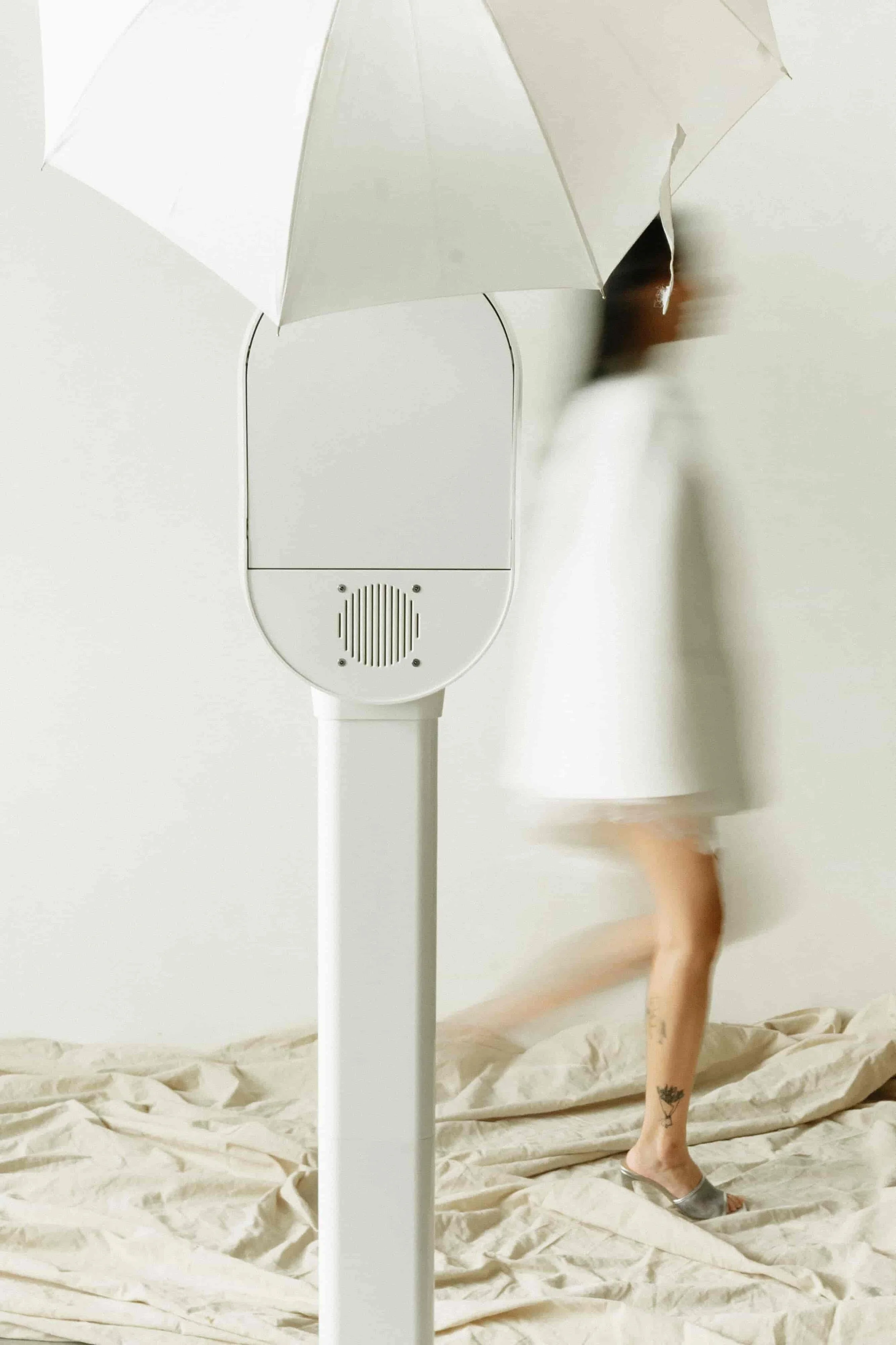 Minimalist modern white photo booth rental setup with studio umbrella and motion blur model - Perfect Capture Booth