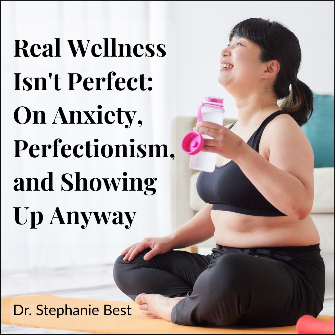 Woman in workout clothes sitting on a yoga mat, smiling and looking up — real wellness and showing up anyway despite anxiety and perfectionism