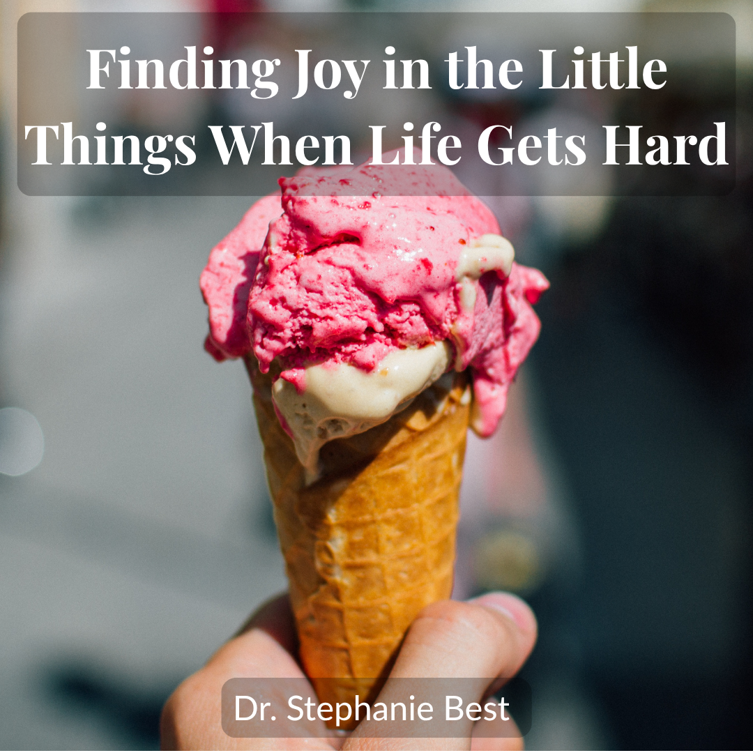 A hand holds a melting raspberry ice cream cone on a sunny street, the kind of small moment that makes finding joy in the little things possible when life gets hard.