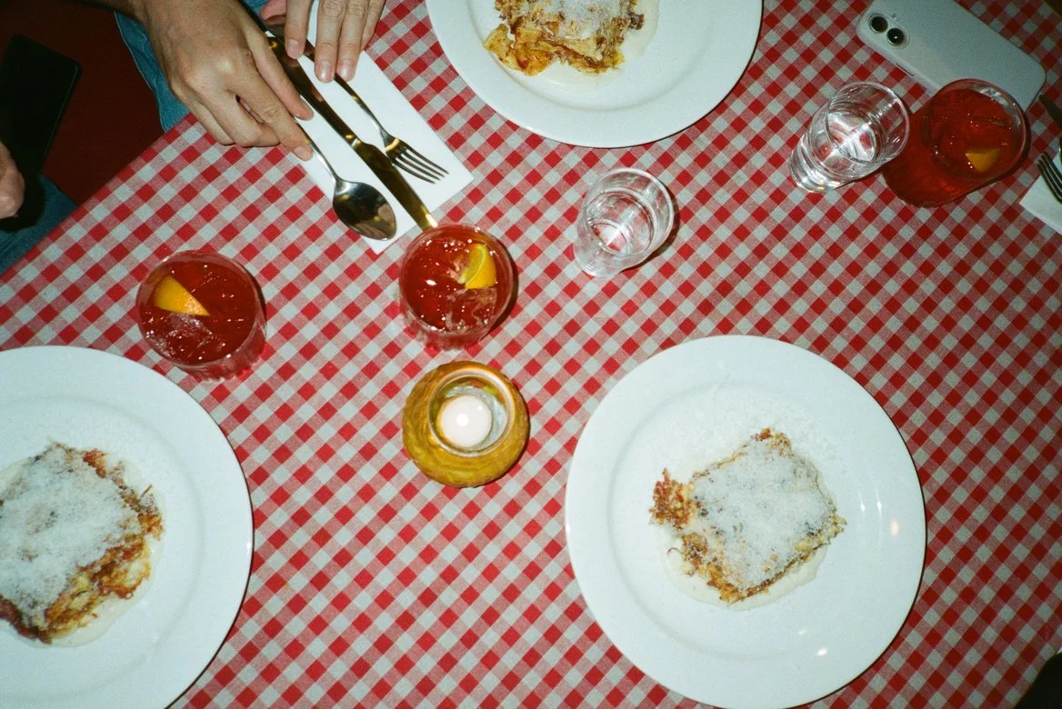 A table at Senza Fondo restuarant: lasagna and negronis on a red checked tablecloth
