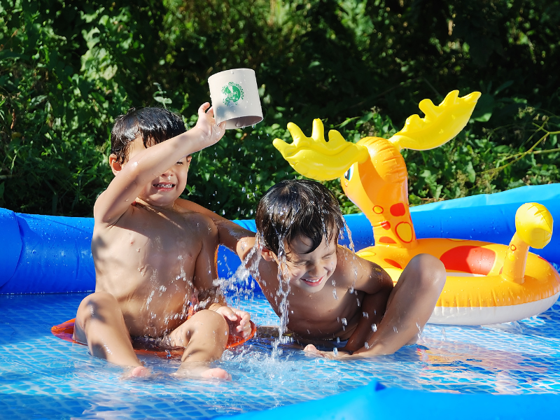Photo of two young children playing in a paddling pool.
