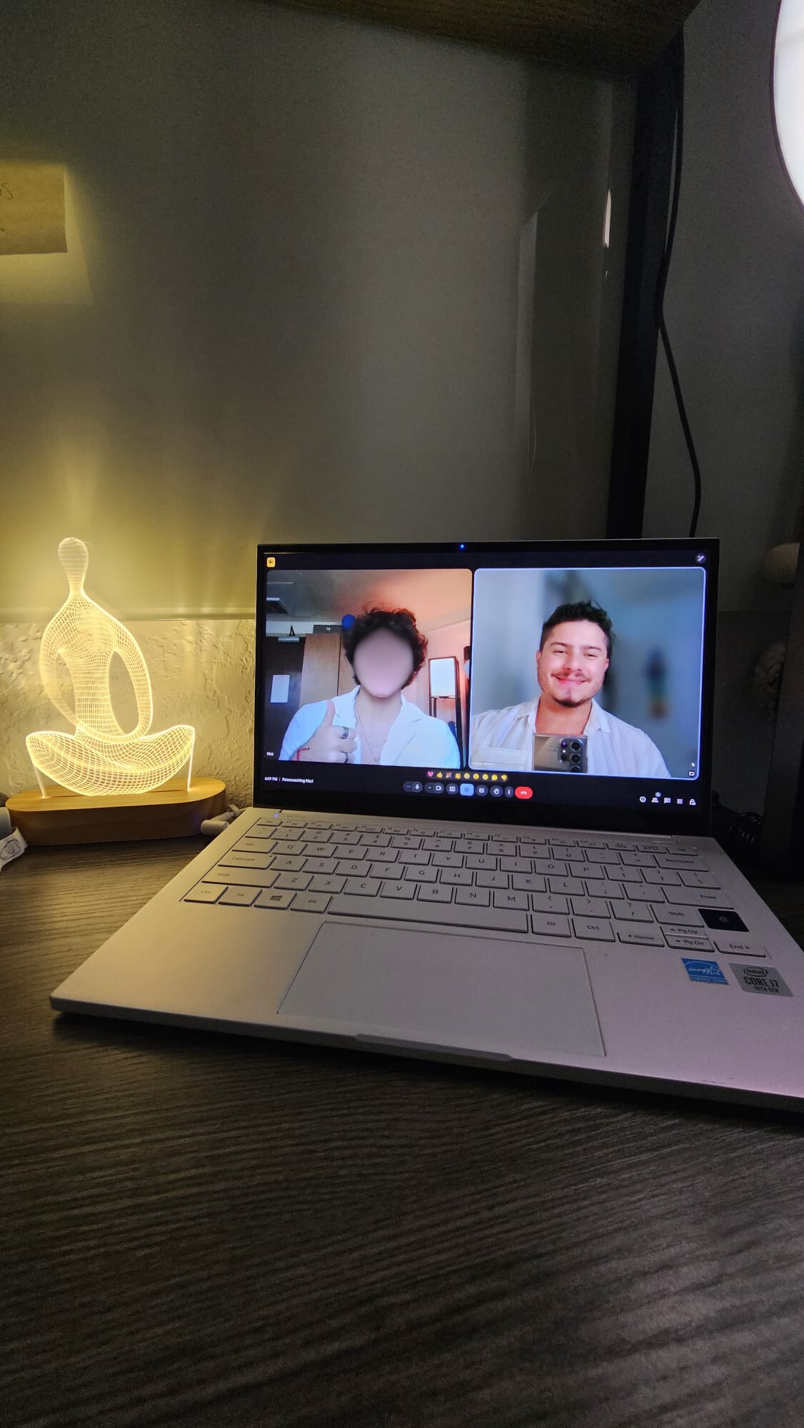 Screen of a video call with a man smiling and holding a phone, blurred and distorted image due to a malfunction or glitch.