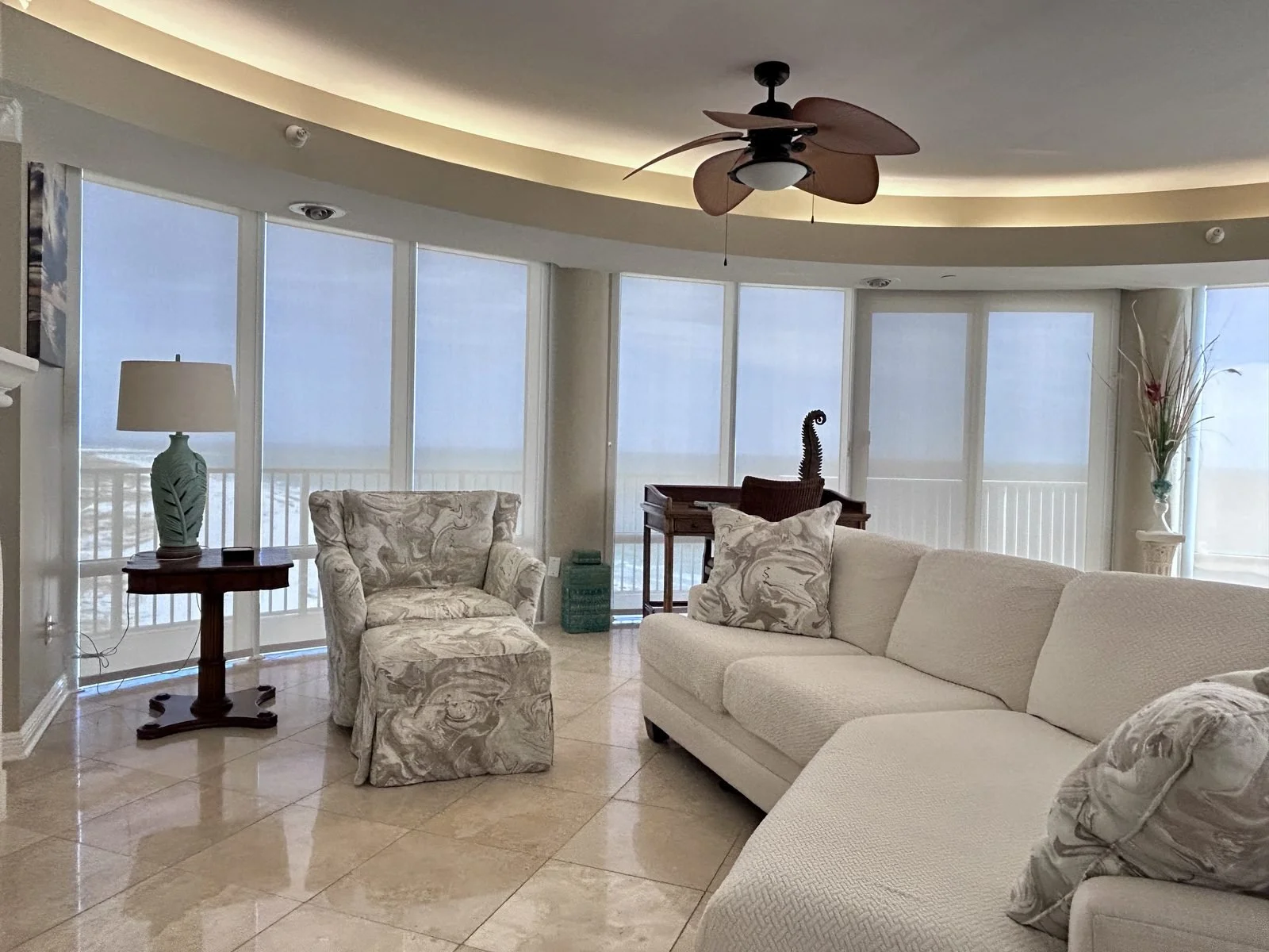 Light Filtering automation shades covering a curved wall of windows in a coastal living room overlooking the Gulf of America. These shades can be controlled with an app from anywhere!
 Location Nautilus Condos